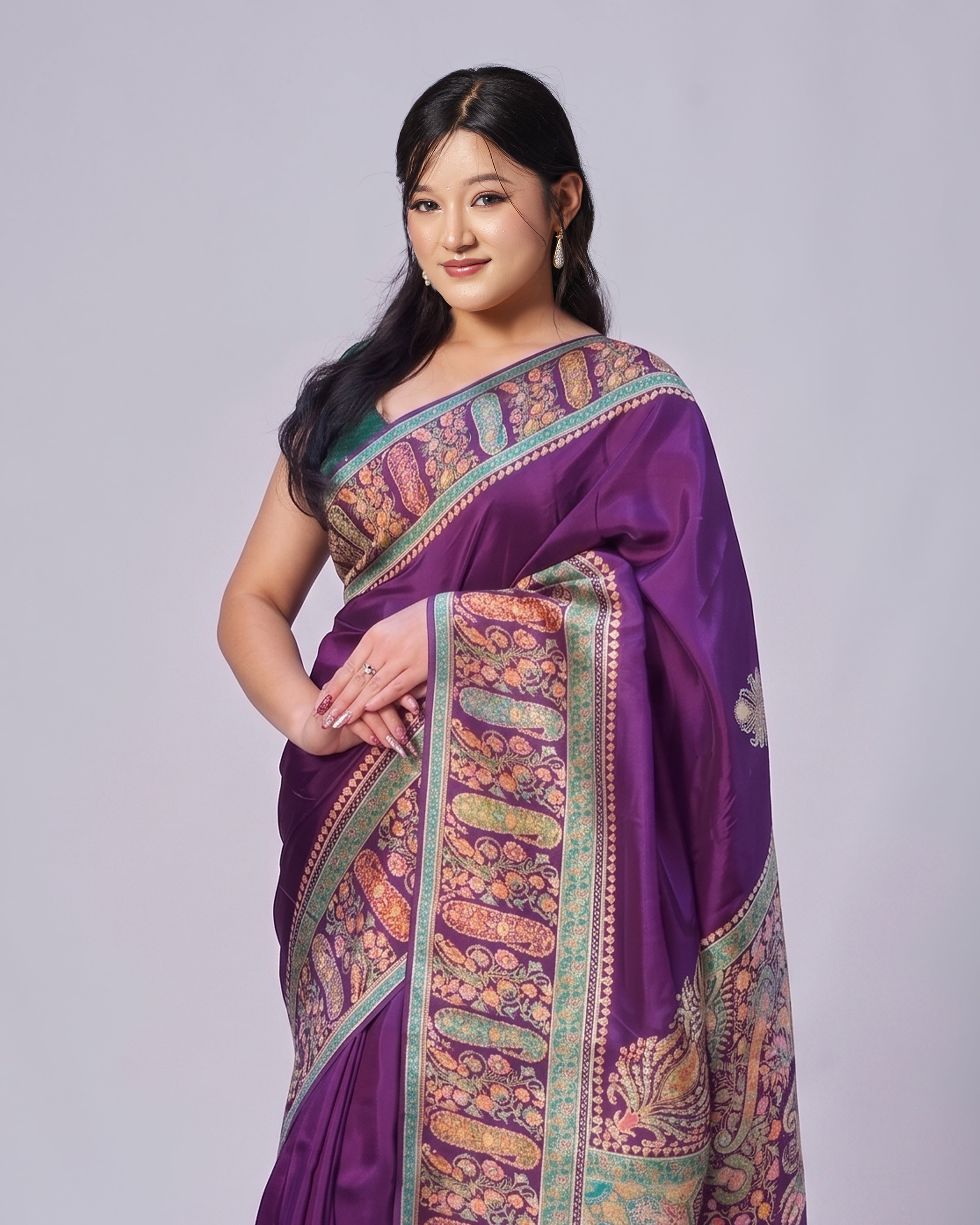 Woman wearing a purple saree with intricate patterns on a plain background