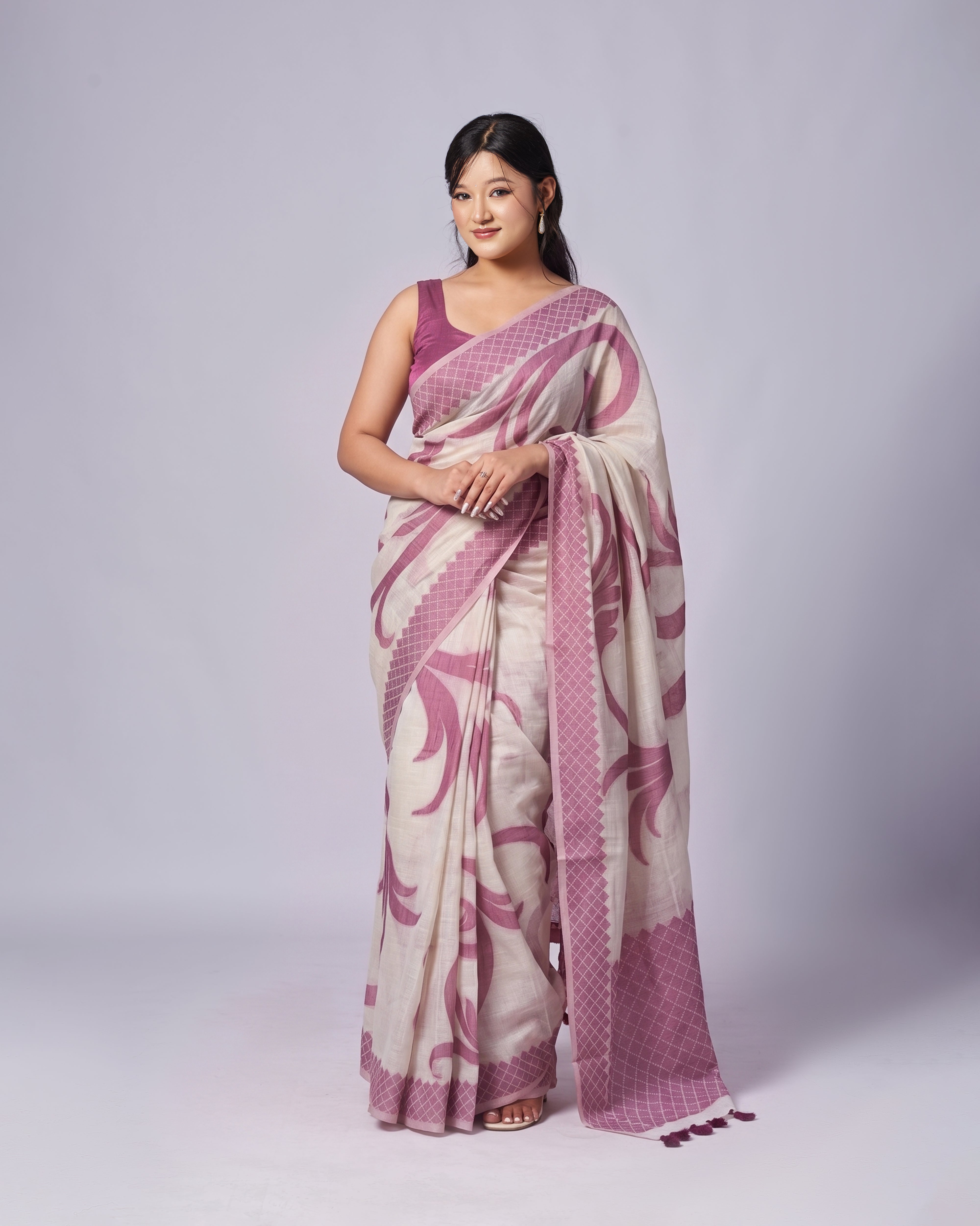 Woman wearing a white and pink saree with a matching blouse on a white background