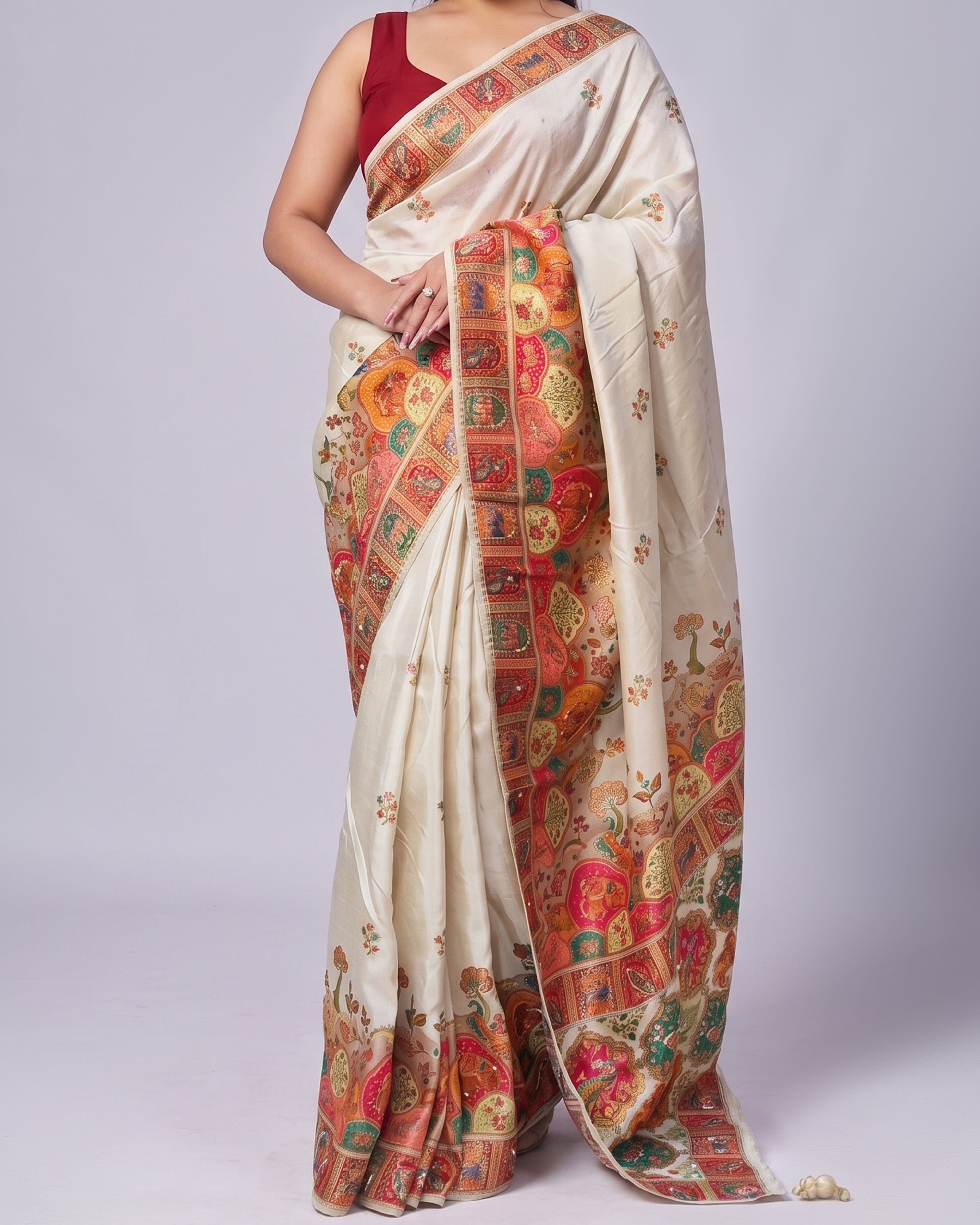 Woman wearing a cream saree with colorful patterns on a white background
