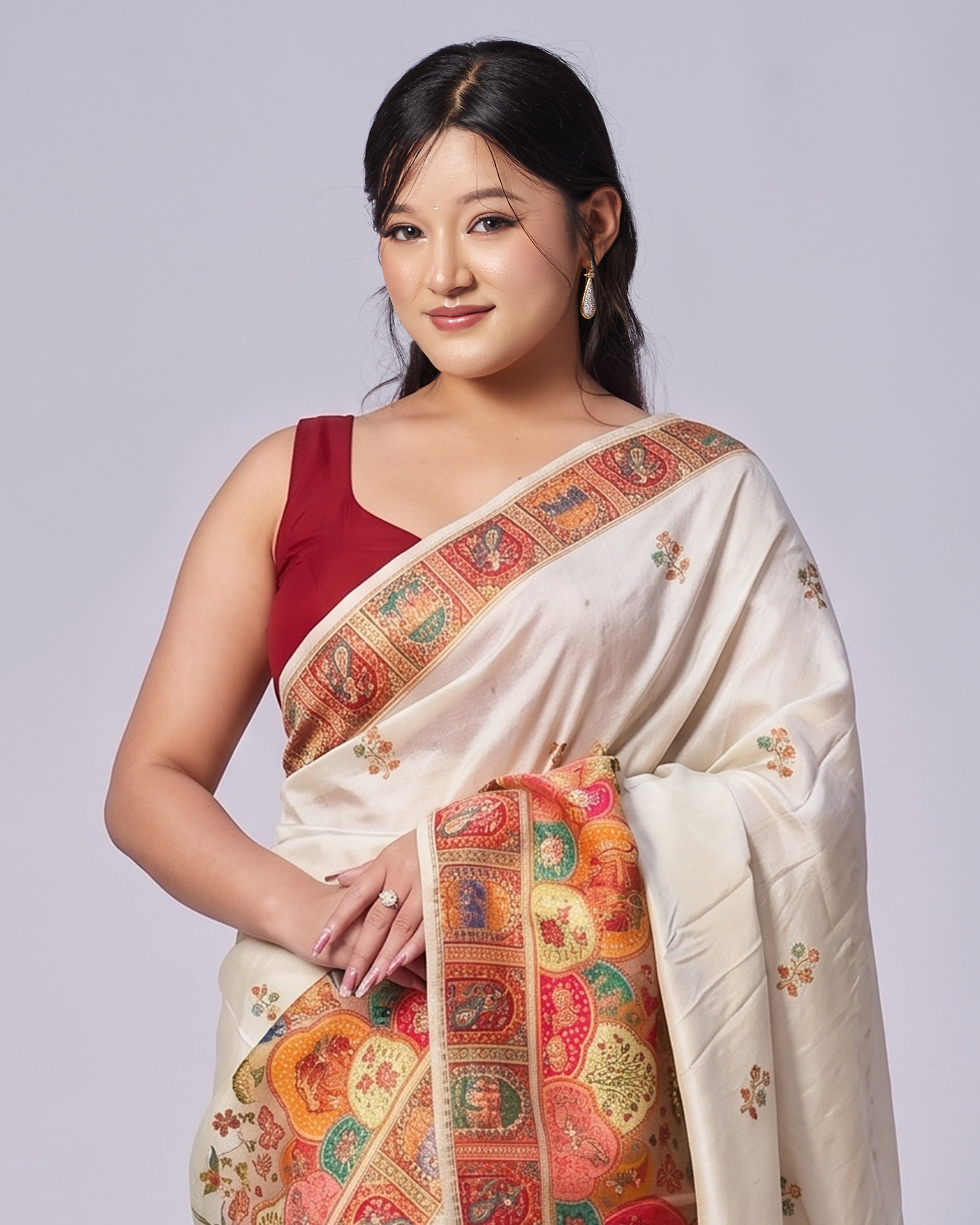 Woman wearing a traditional saree with intricate patterns on a plain background