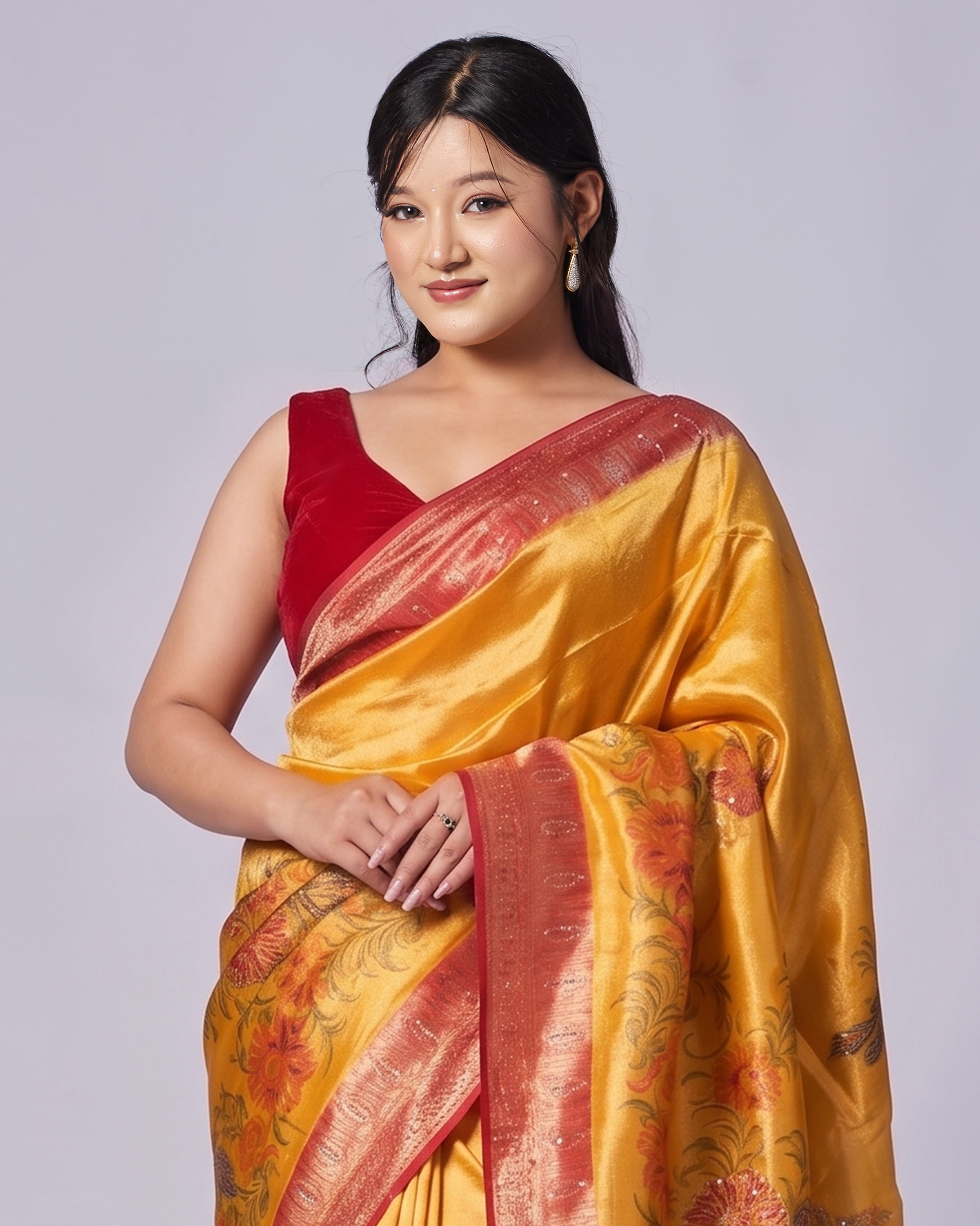 Woman wearing a yellow and red saree on a light gray background