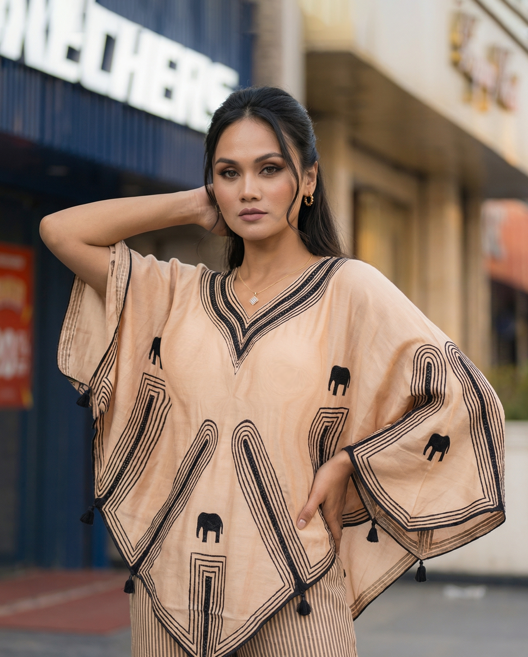 Woman wearing a beige outfit with black patterns in an urban setting