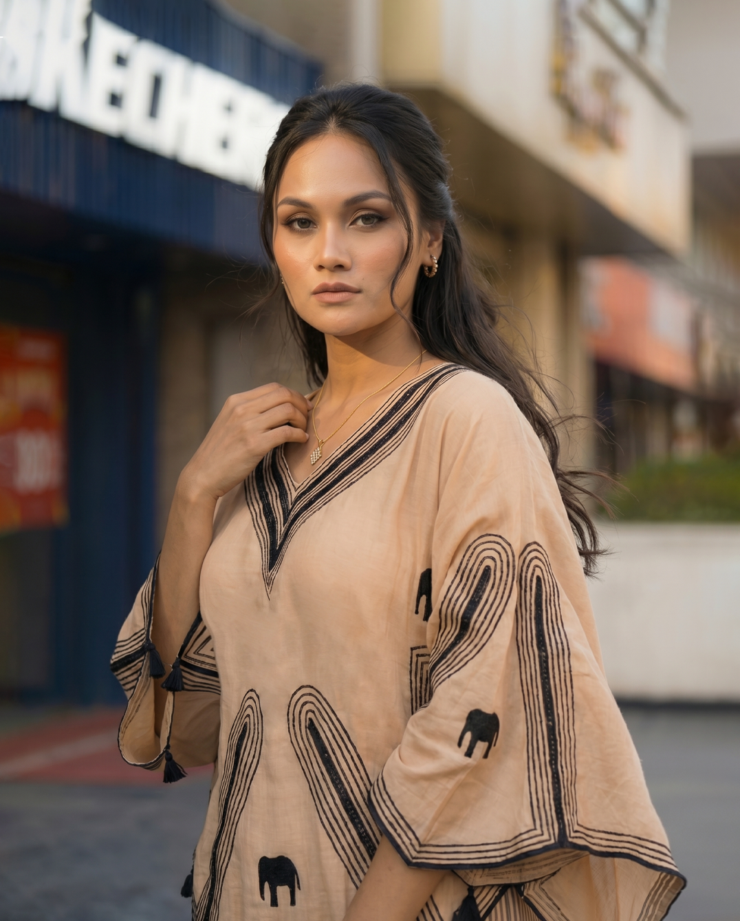 Woman wearing a beige outfit with black patterns in an urban setting