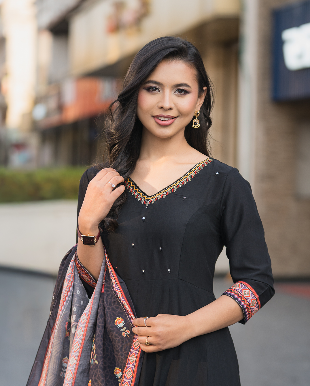 Woman in a black traditional outfit with colorful patterns outdoors