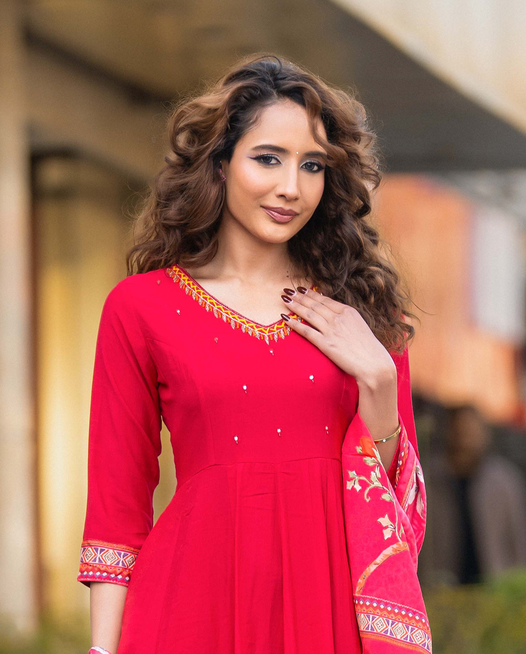 Woman wearing a red dress with intricate patterns in an outdoor setting