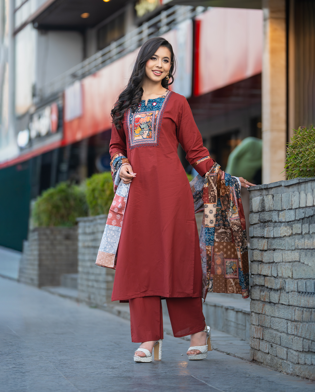 Woman in a traditional outfit standing on a street with a blurred background