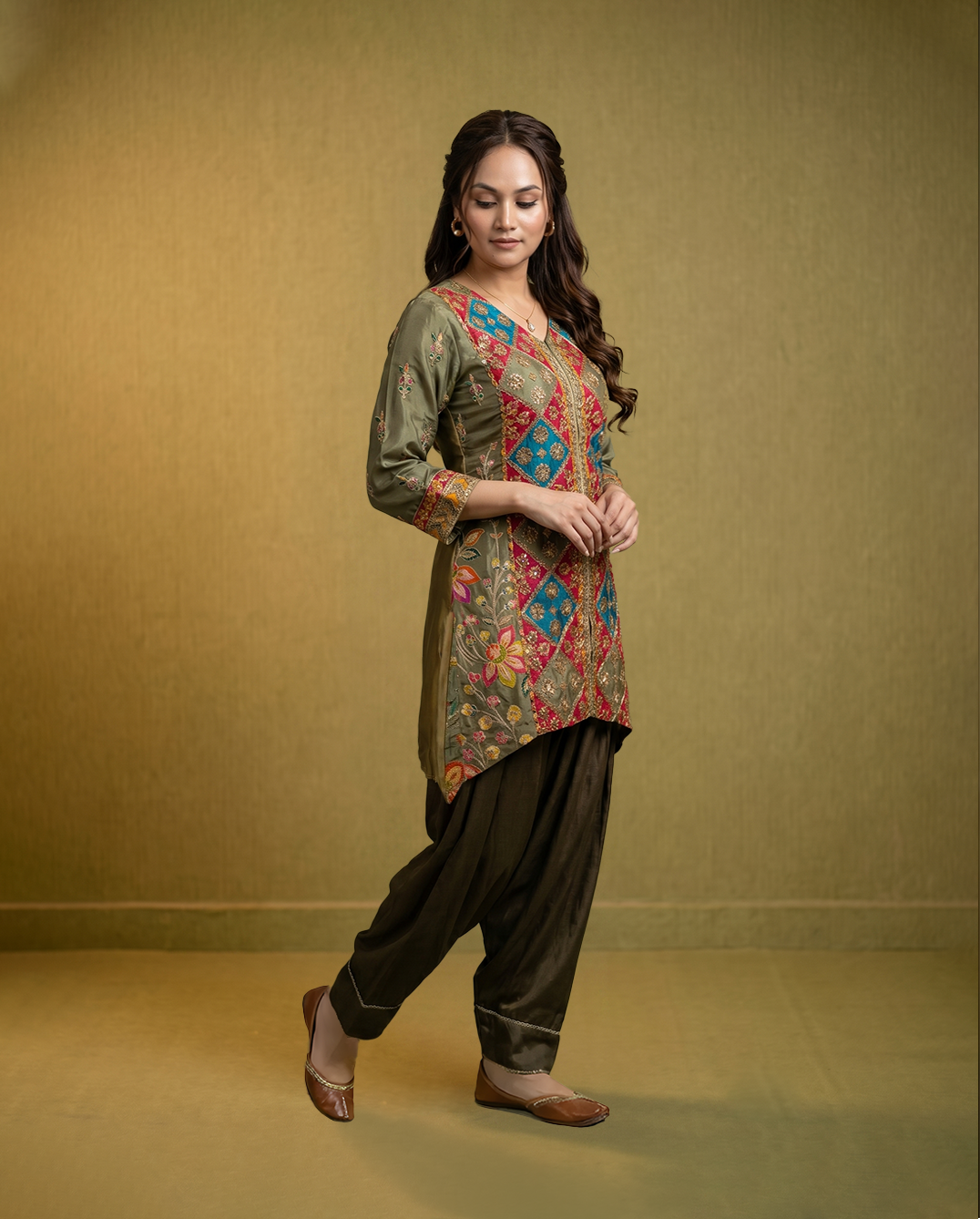 Woman wearing a traditional outfit with a colorful top and dark pants on a beige background