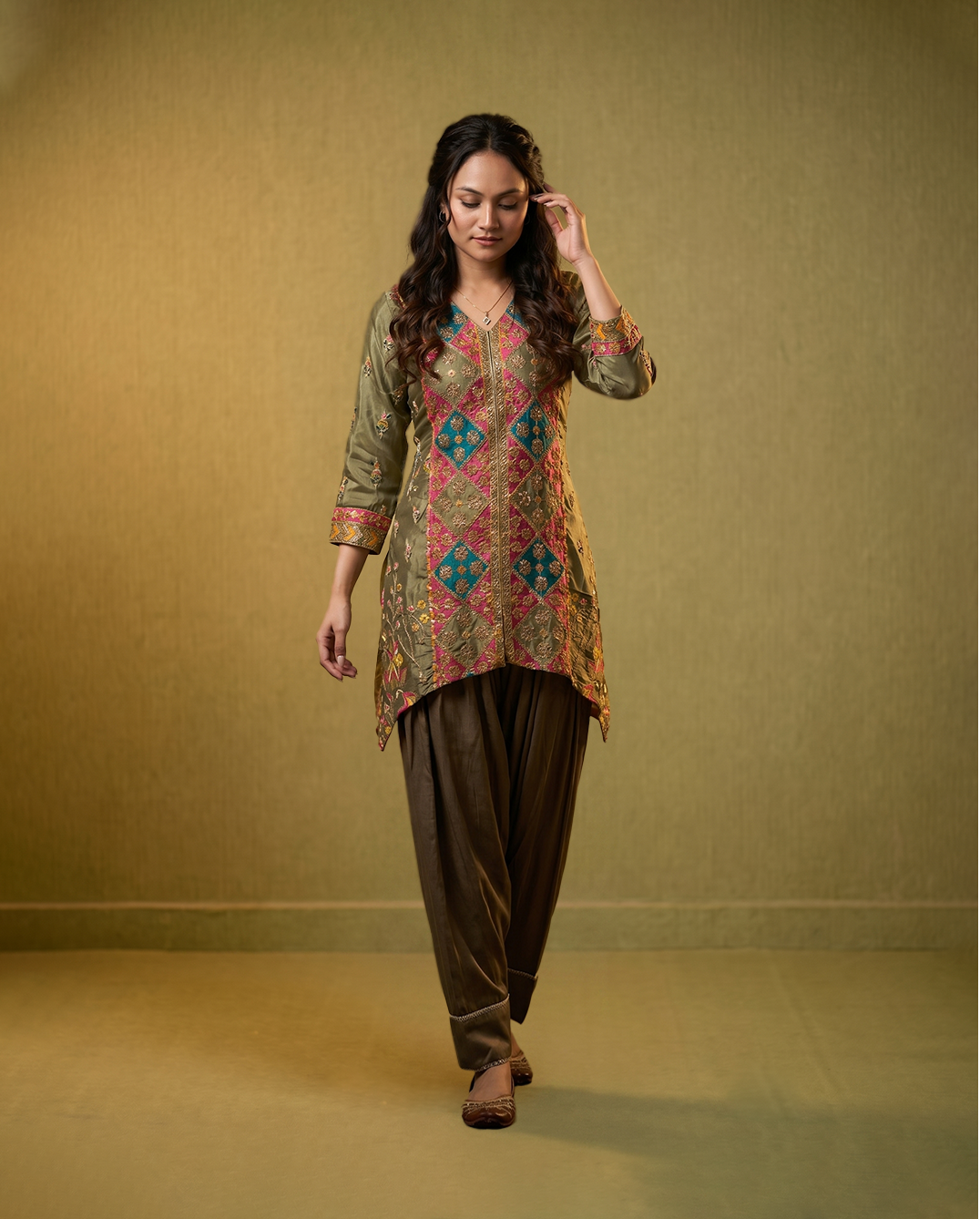 Woman wearing a patterned kurta with brown pants against a green background