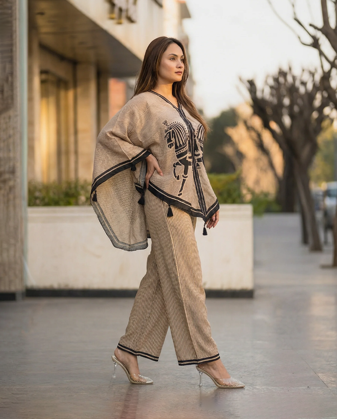 Woman wearing a beige outfit with a patterned shawl in an urban setting