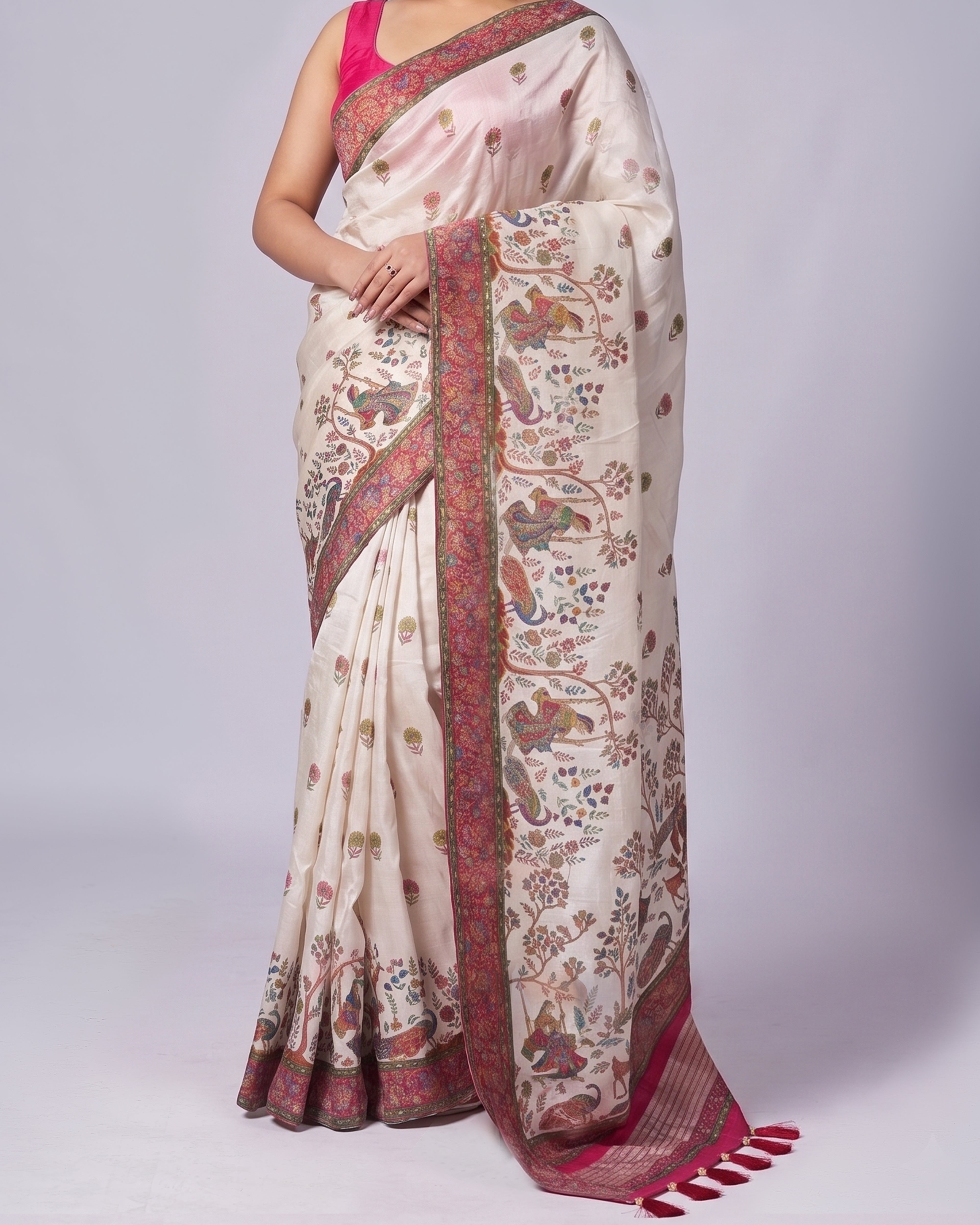 Woman wearing a cream saree with intricate patterns and a pink blouse on a white background