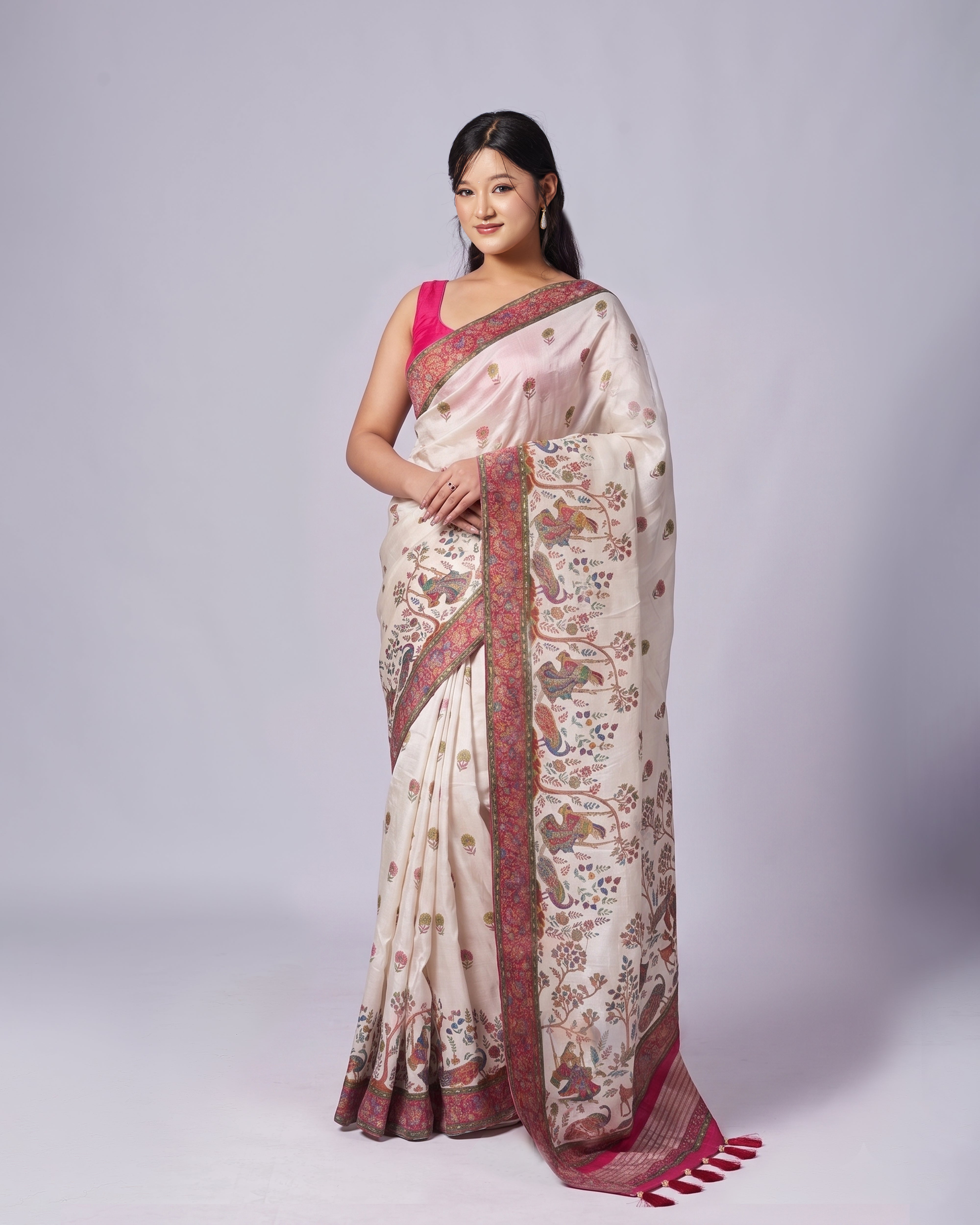 Woman wearing a traditional saree with a white and pink design on a plain background