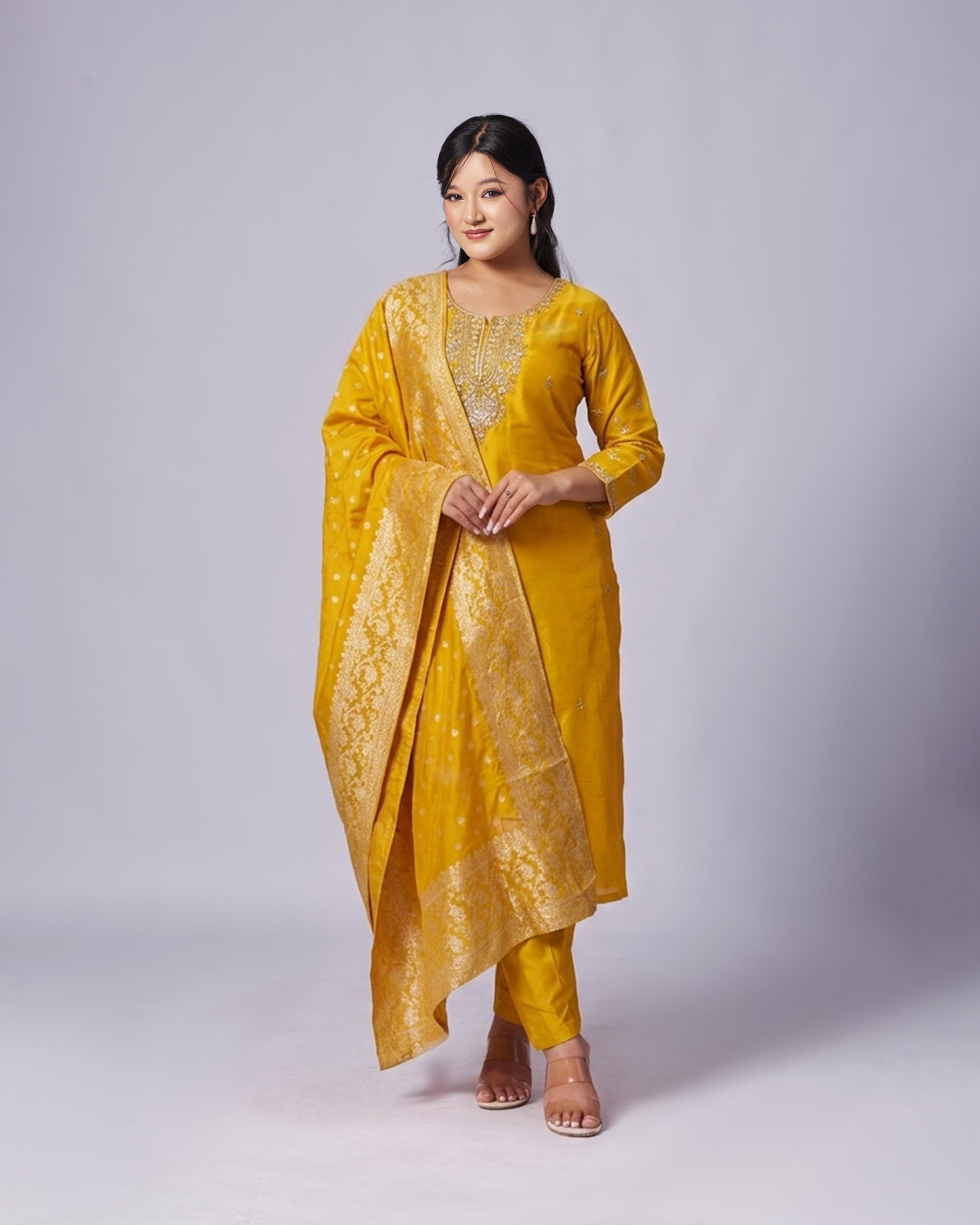 Woman wearing a yellow traditional outfit with a plain background