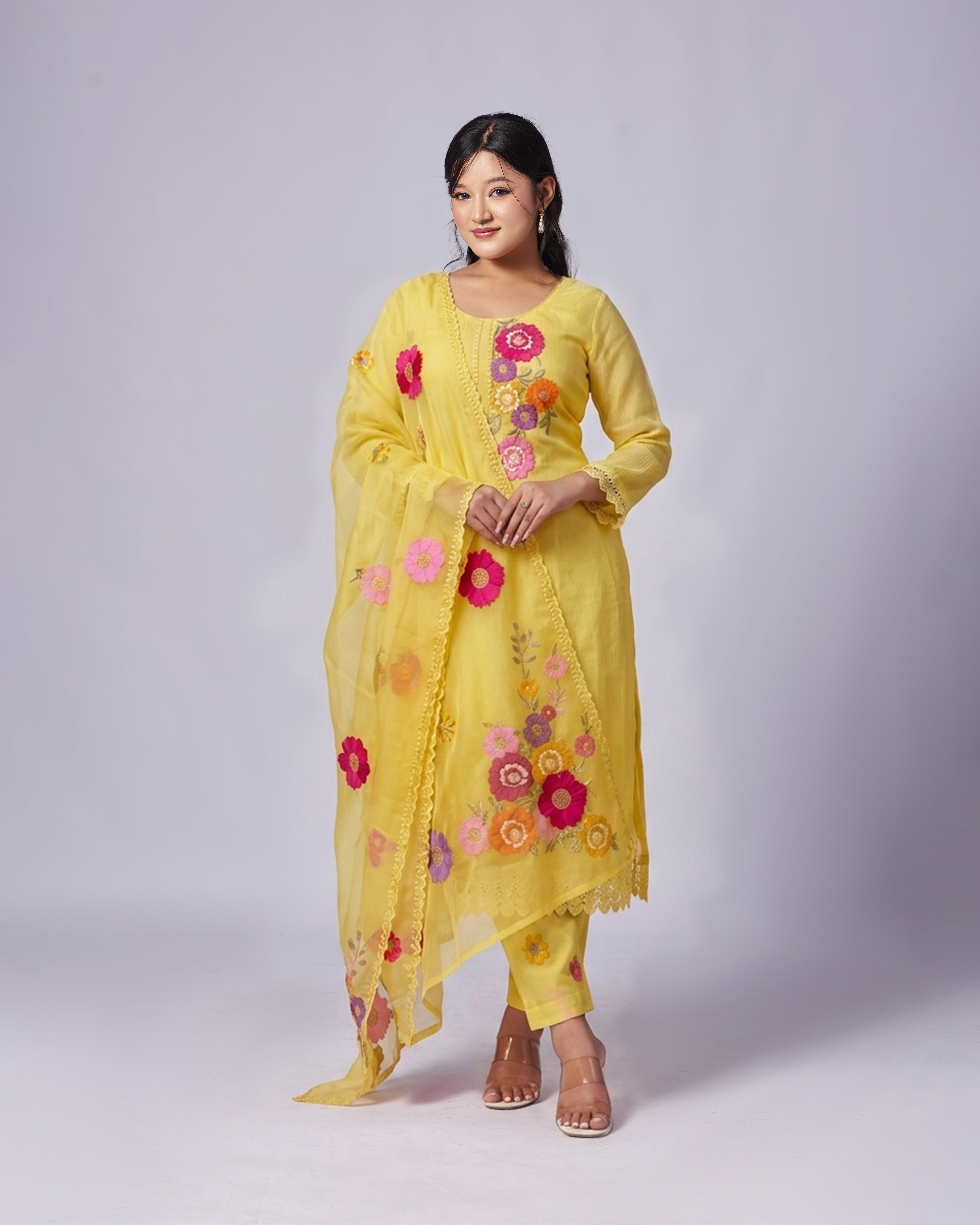 Woman wearing a yellow outfit with floral patterns on a white background