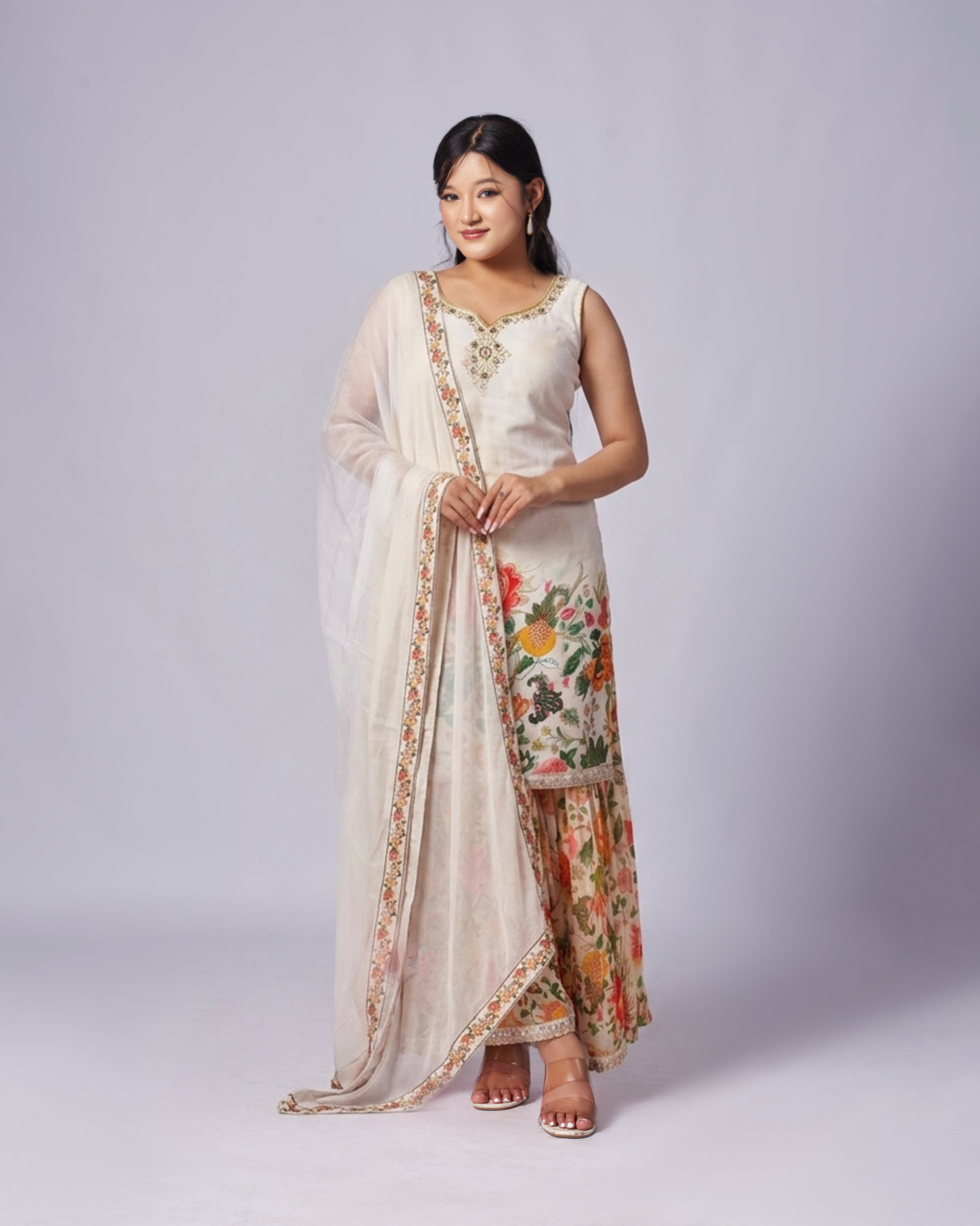 Woman wearing a traditional outfit with a floral kurthi set on a plain background