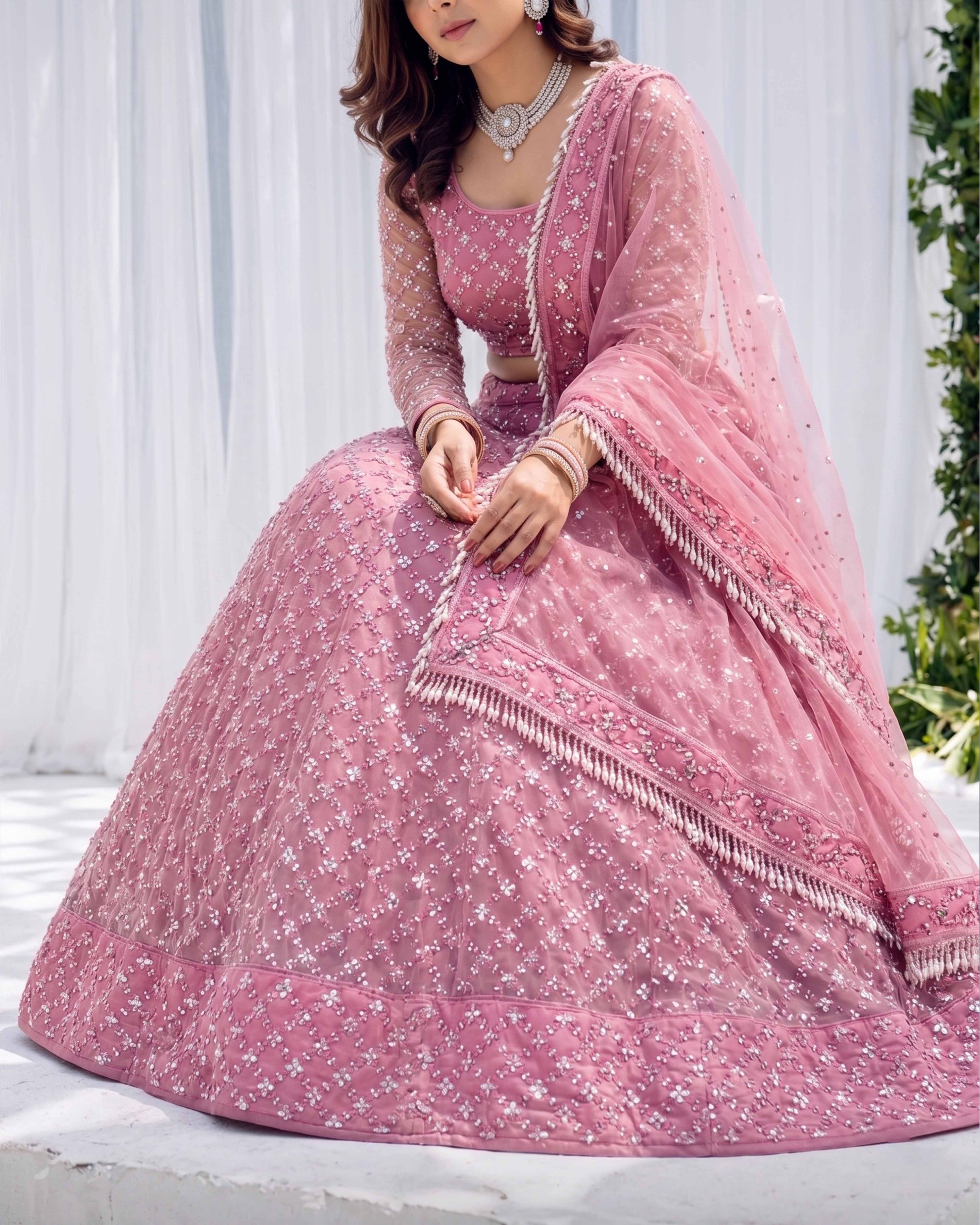 Woman wearing a pink embroidered traditional outfit with a white background