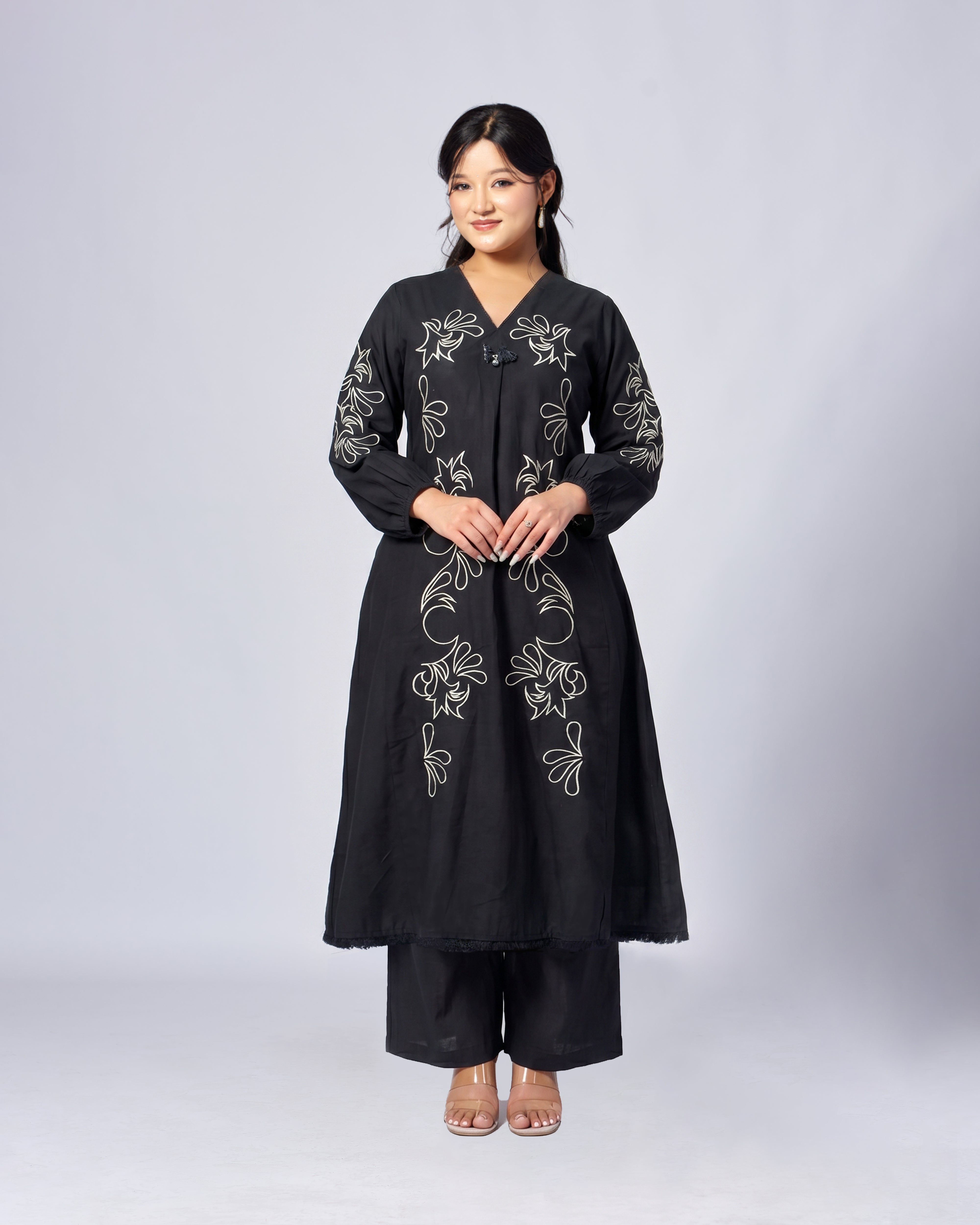 Woman wearing a black embroidered outfit on a white background