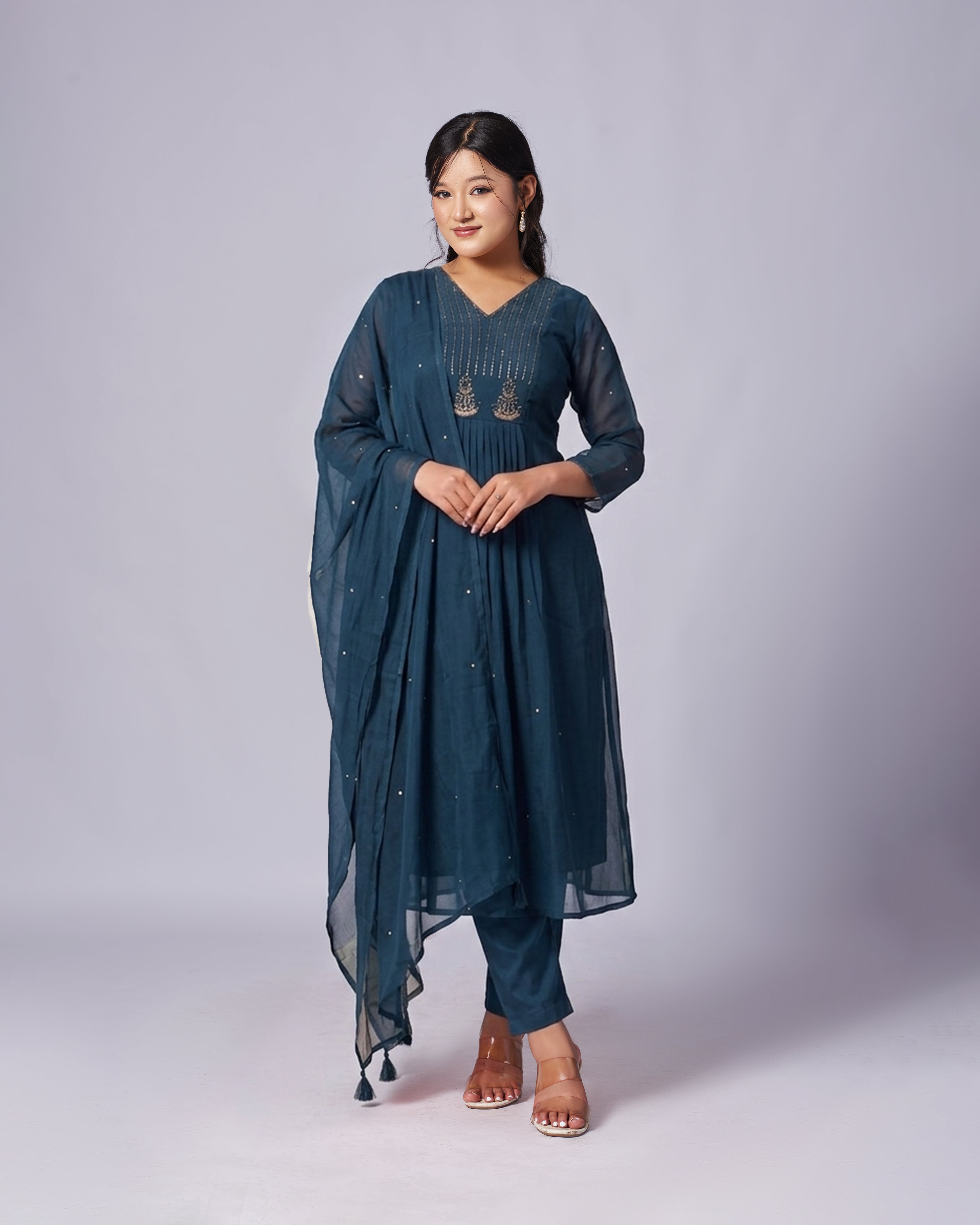 Woman wearing a teal traditional outfit with a plain background