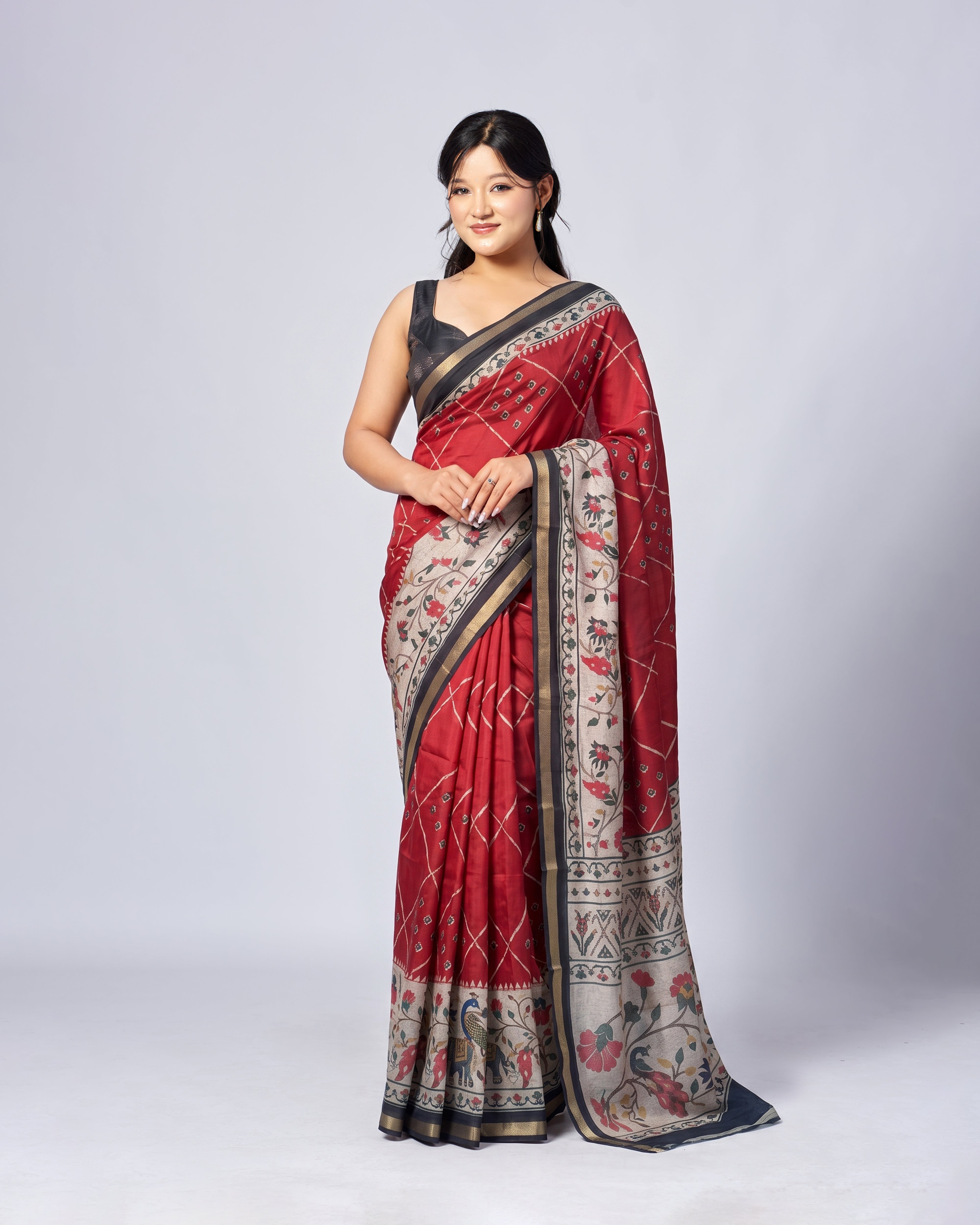 Woman wearing a red saree with intricate patterns on a white background