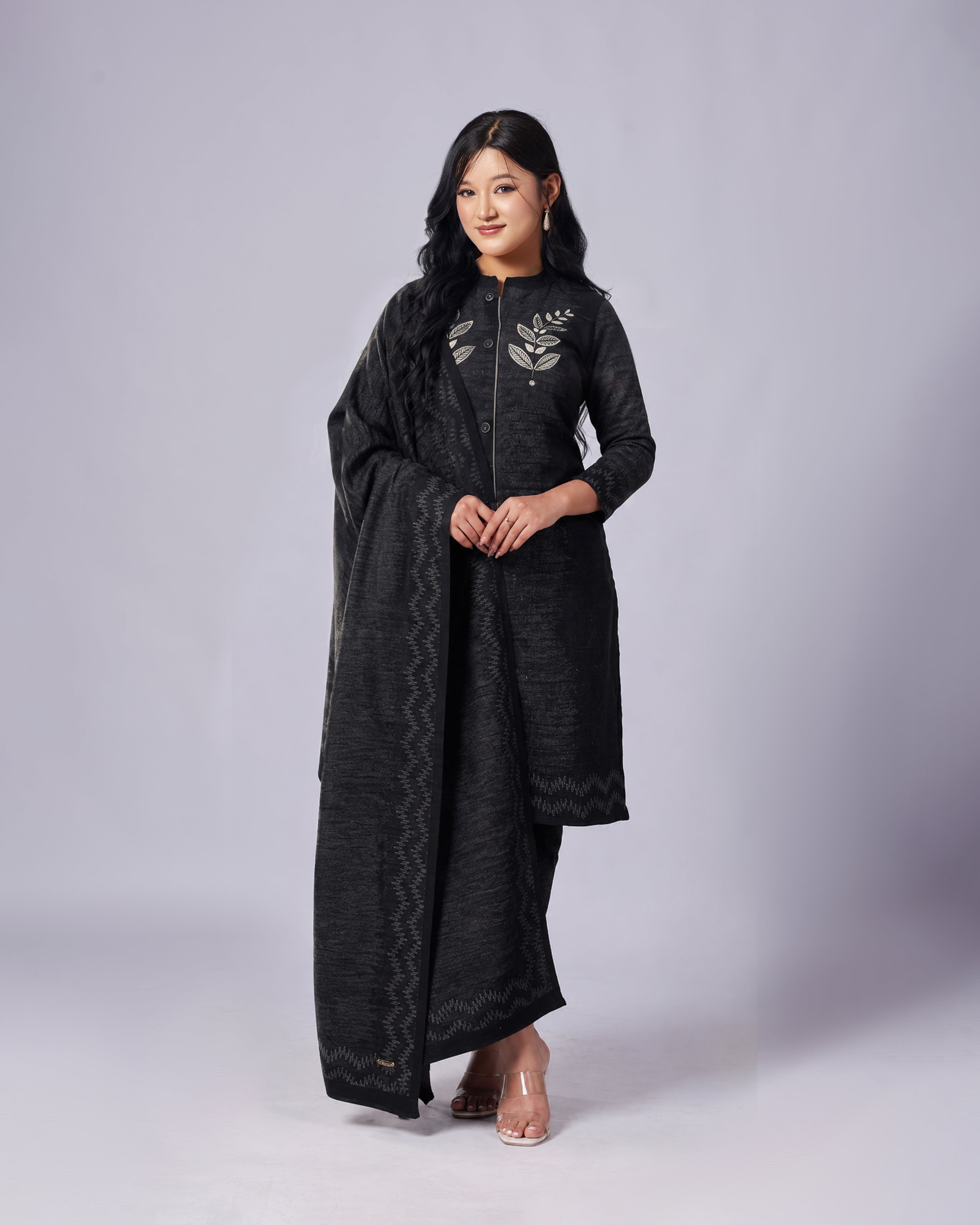Woman wearing a black embroidered dress on a gray background