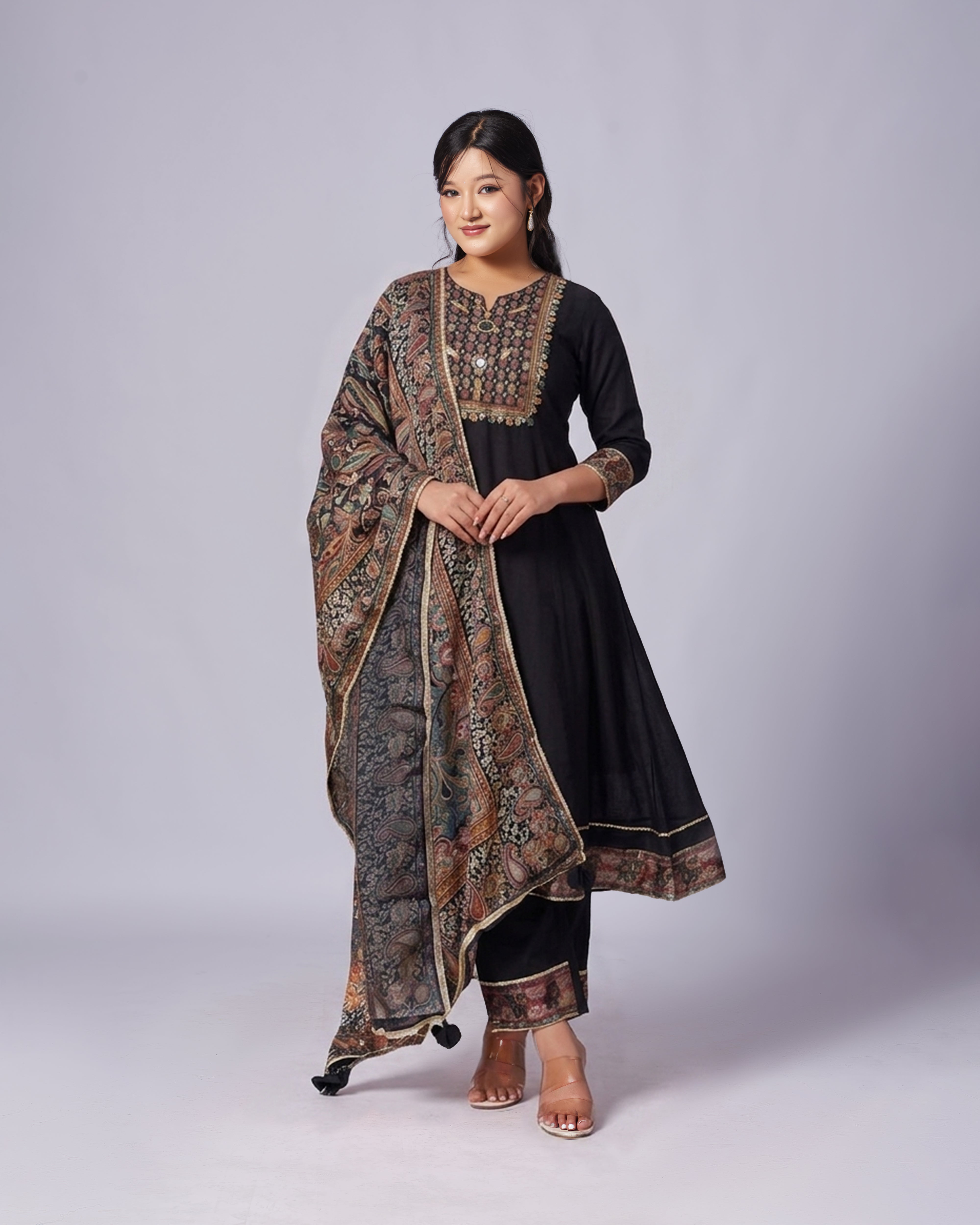 Woman wearing a black outfit with a patterned shawl on a white background