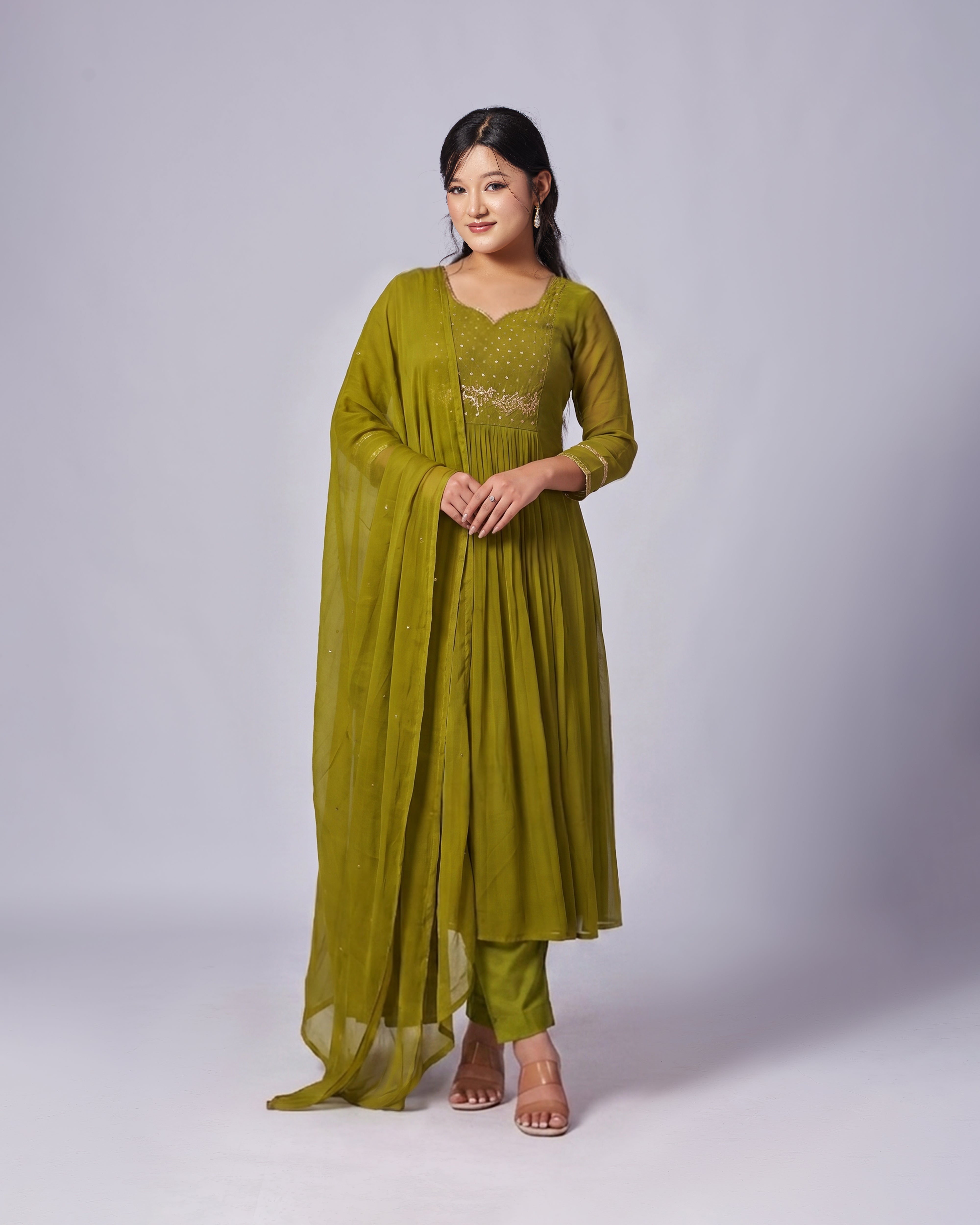 Woman wearing a green traditional outfit with a plain background