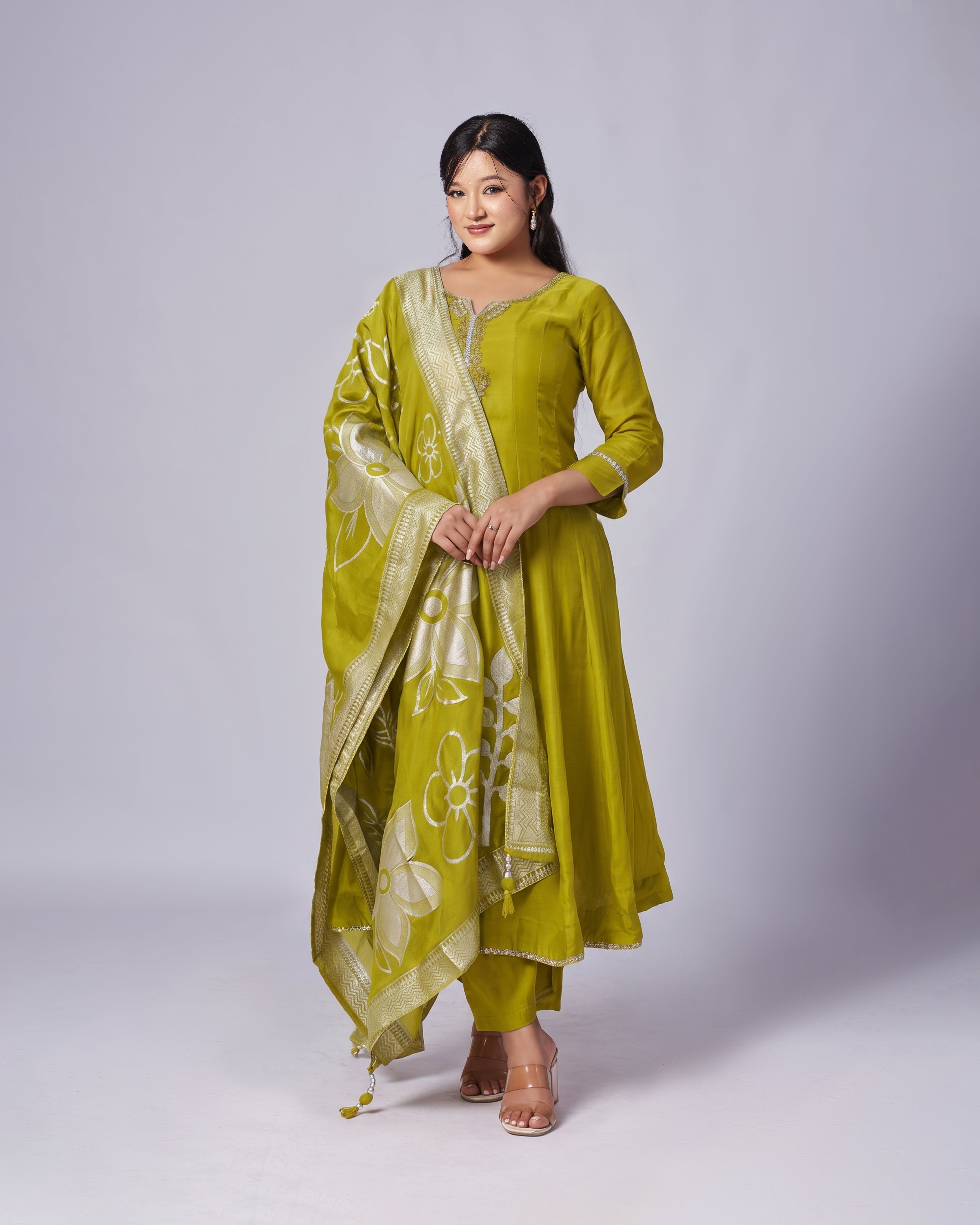 Woman wearing a green traditional outfit with a matching dupatta on a white background