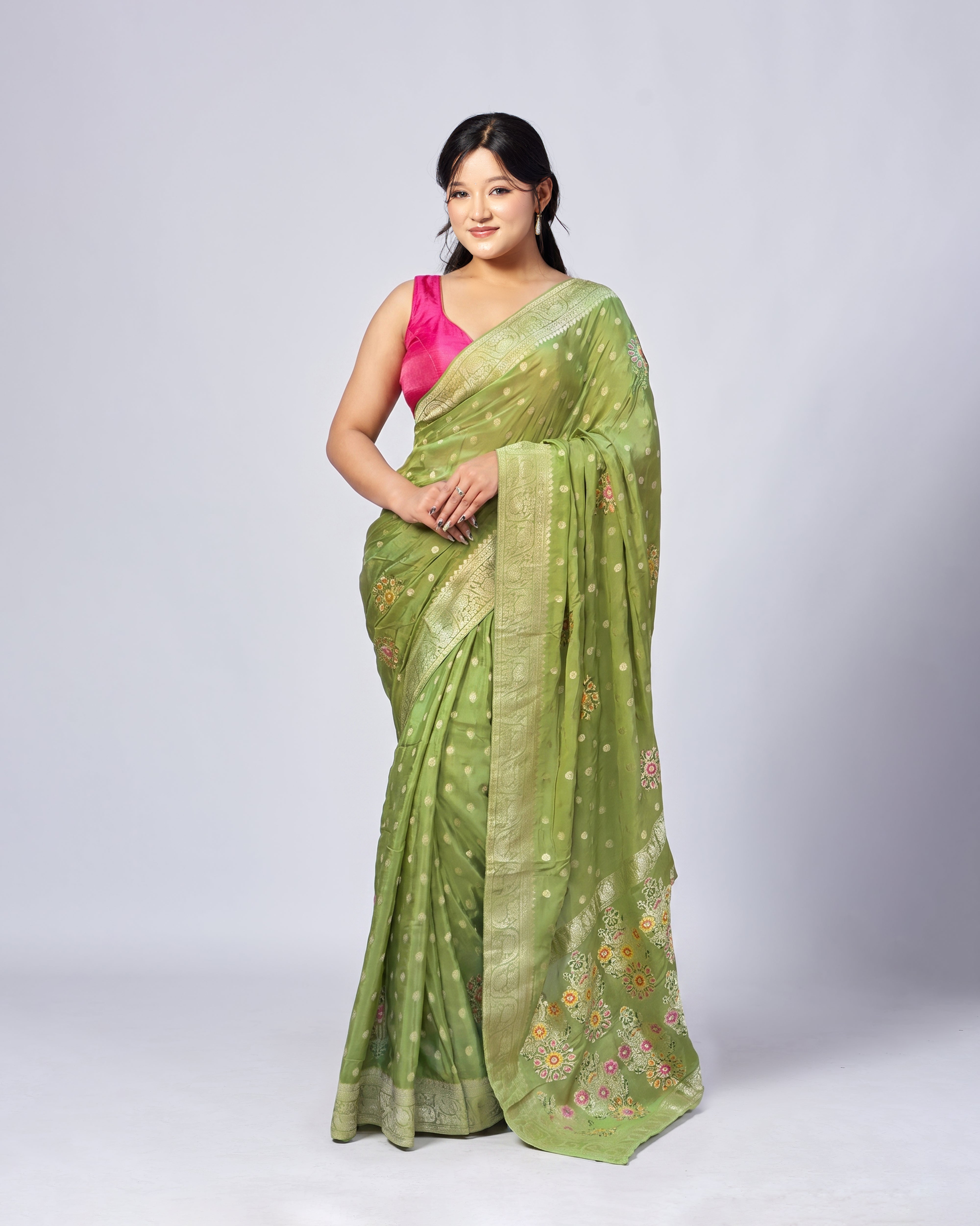 Woman wearing a green saree with a pink blouse on a white background