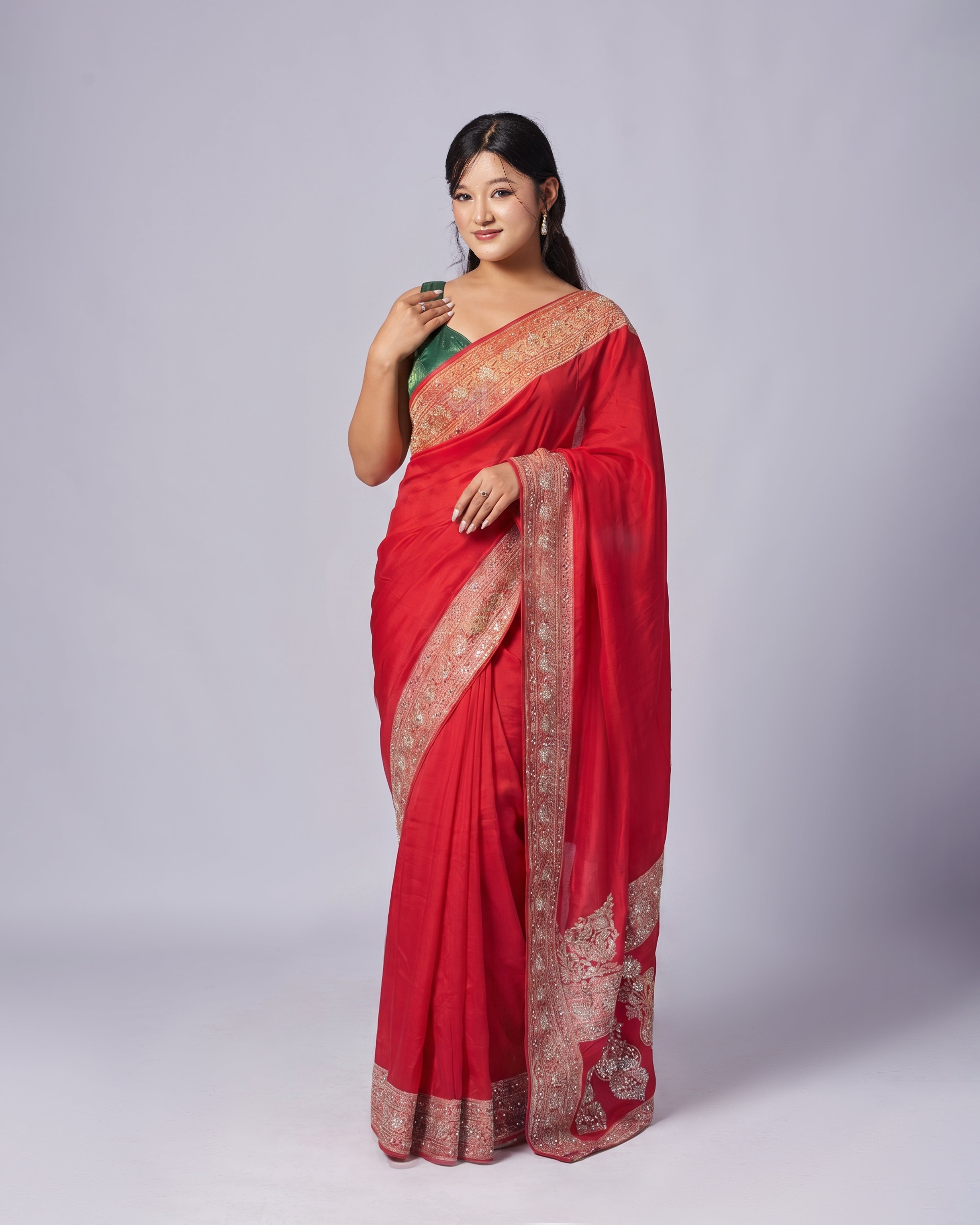 Woman wearing a red saree with gold patterns on a white background