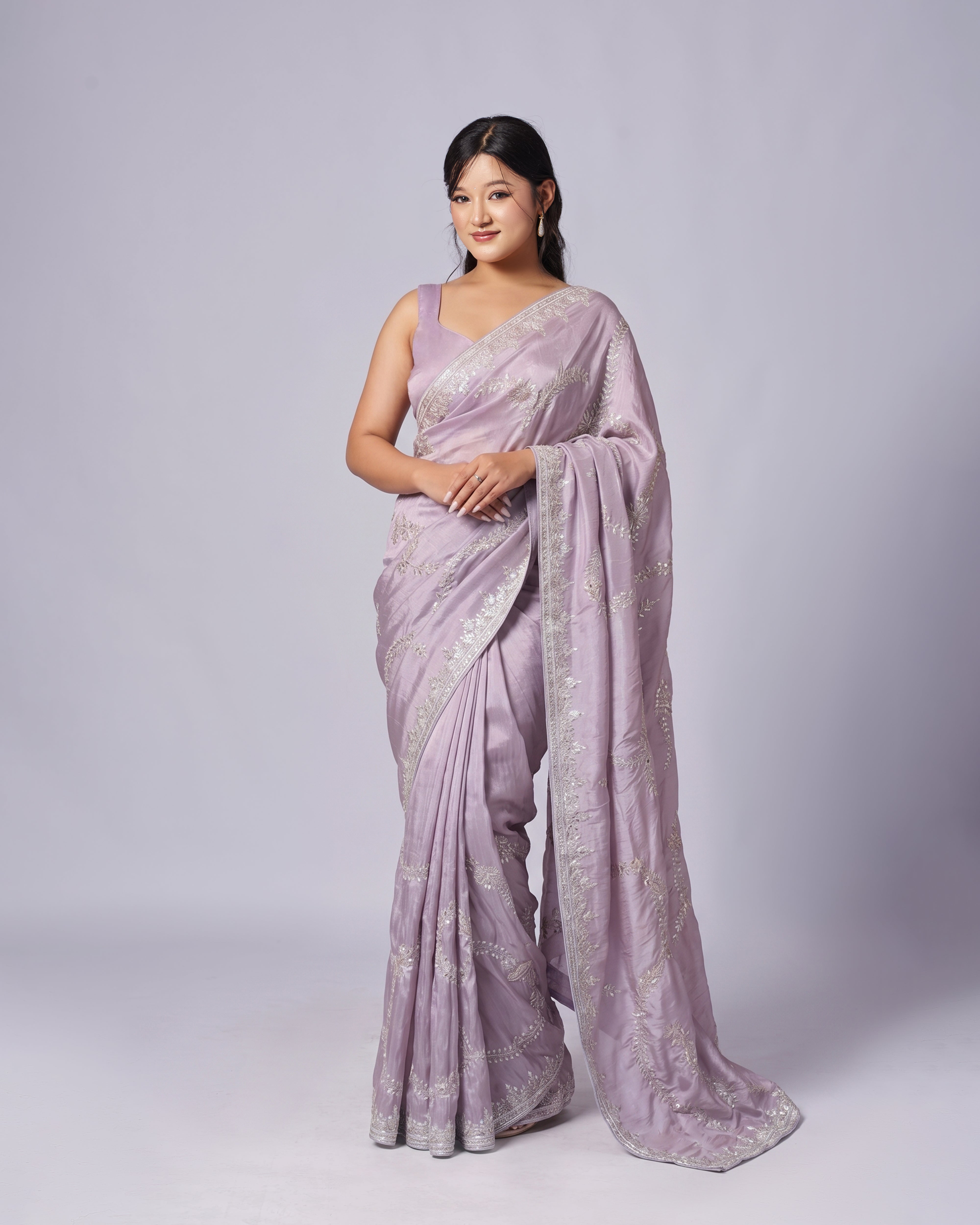 Woman wearing a lavender saree with a white border on a light gray background