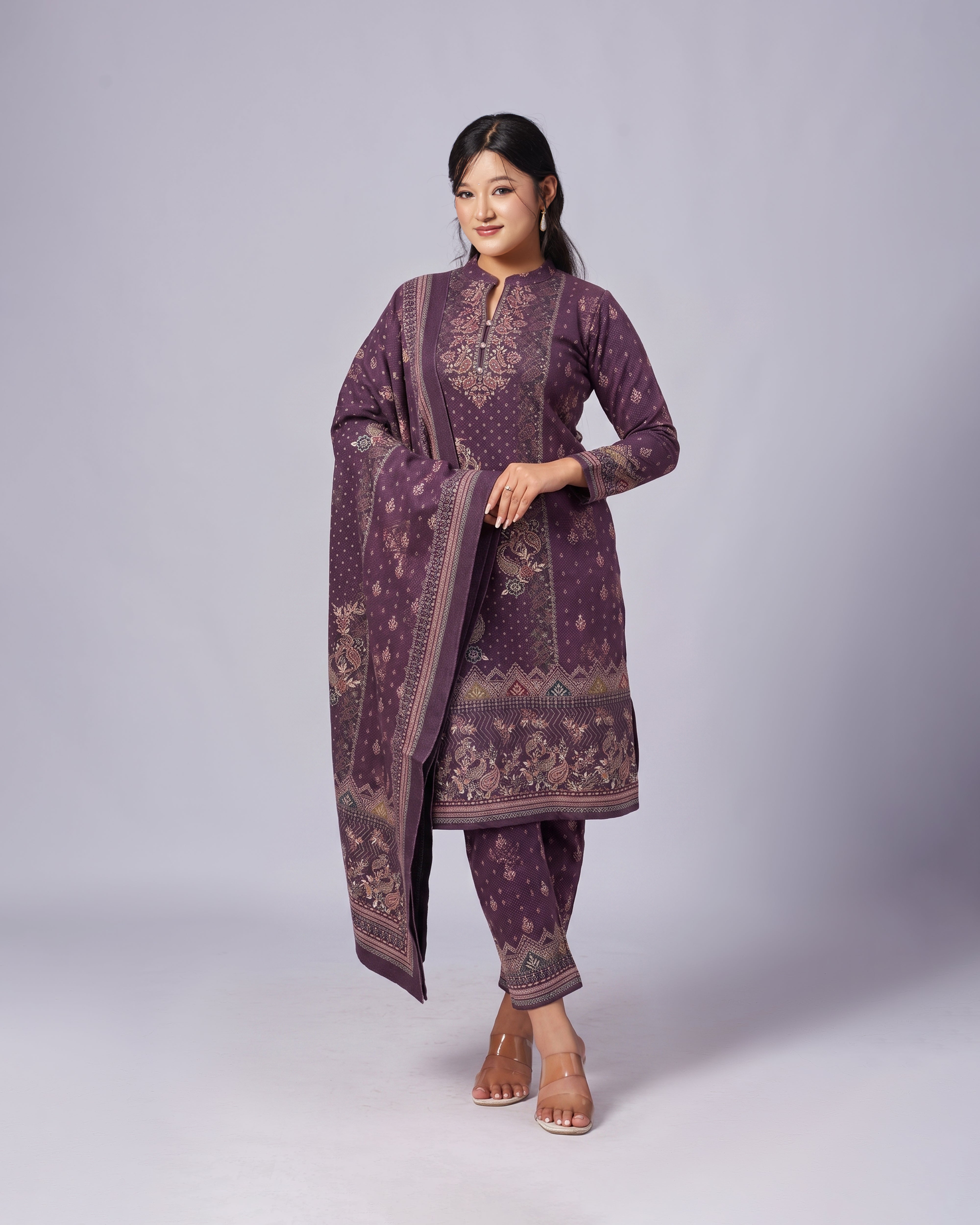 Woman wearing a purple embroidered traditional outfit on a light gray background