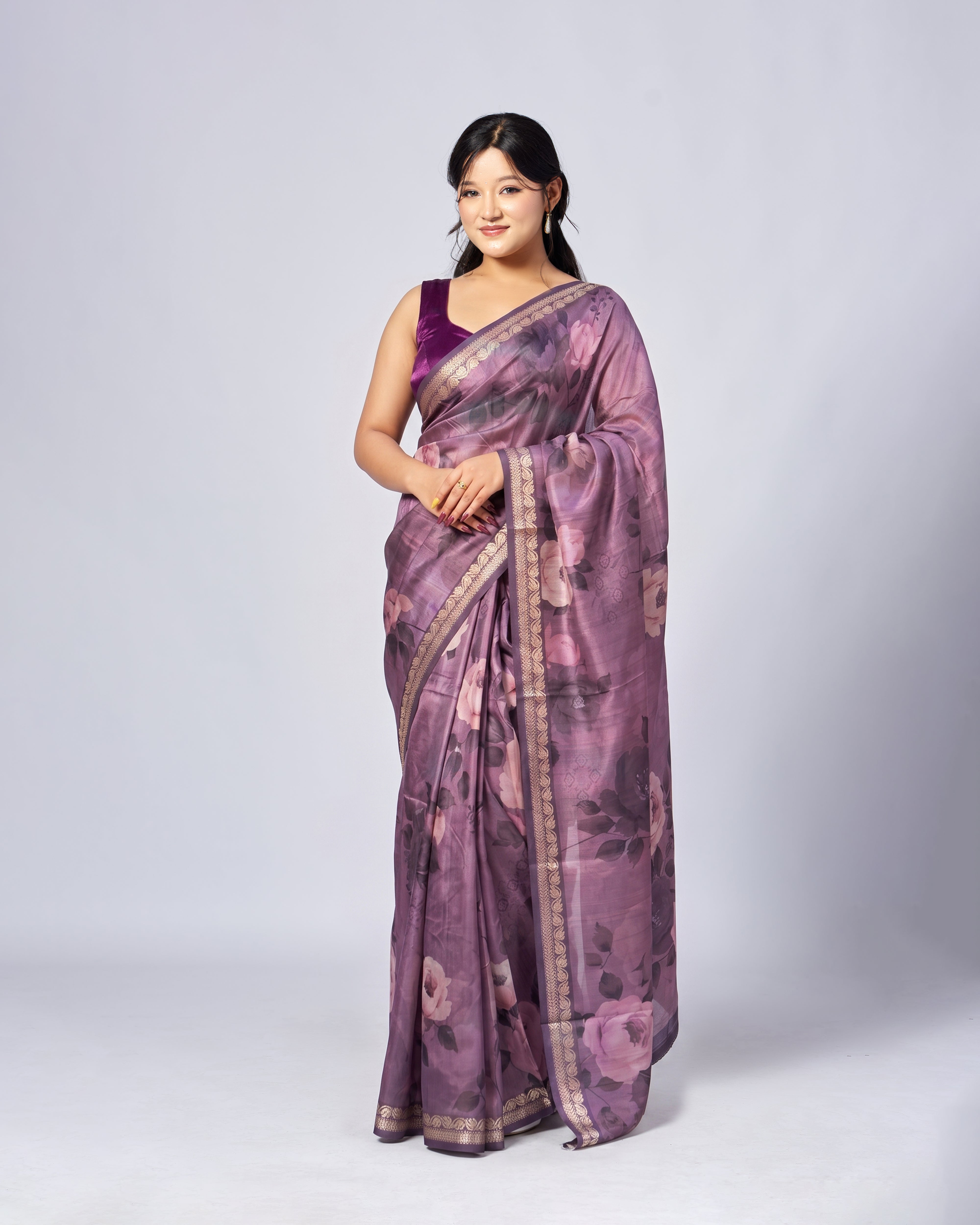 Woman wearing a purple saree with a floral pattern on a white background