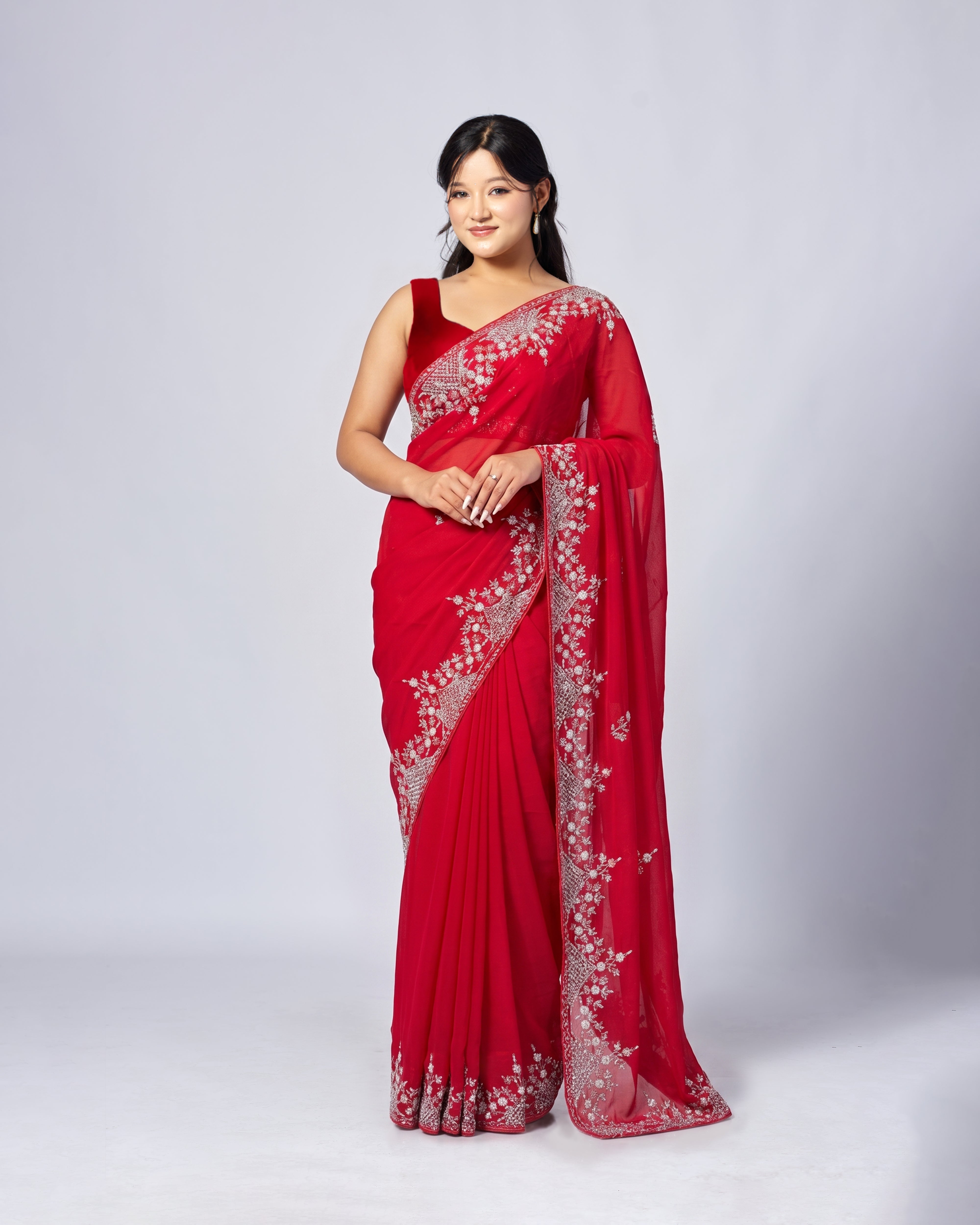 Woman wearing a red saree with white embroidery on a white background