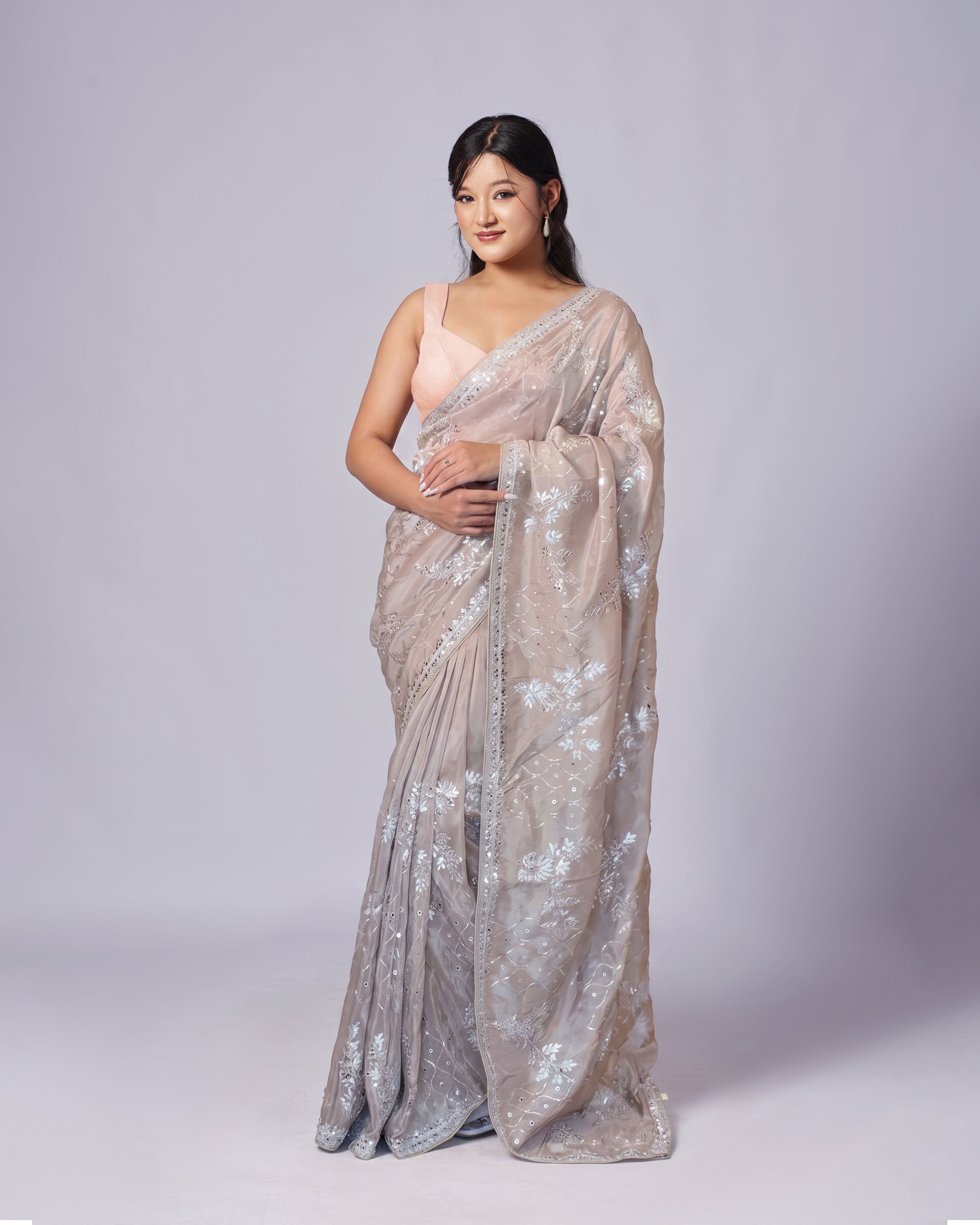 Woman wearing a sparkling saree on a plain background