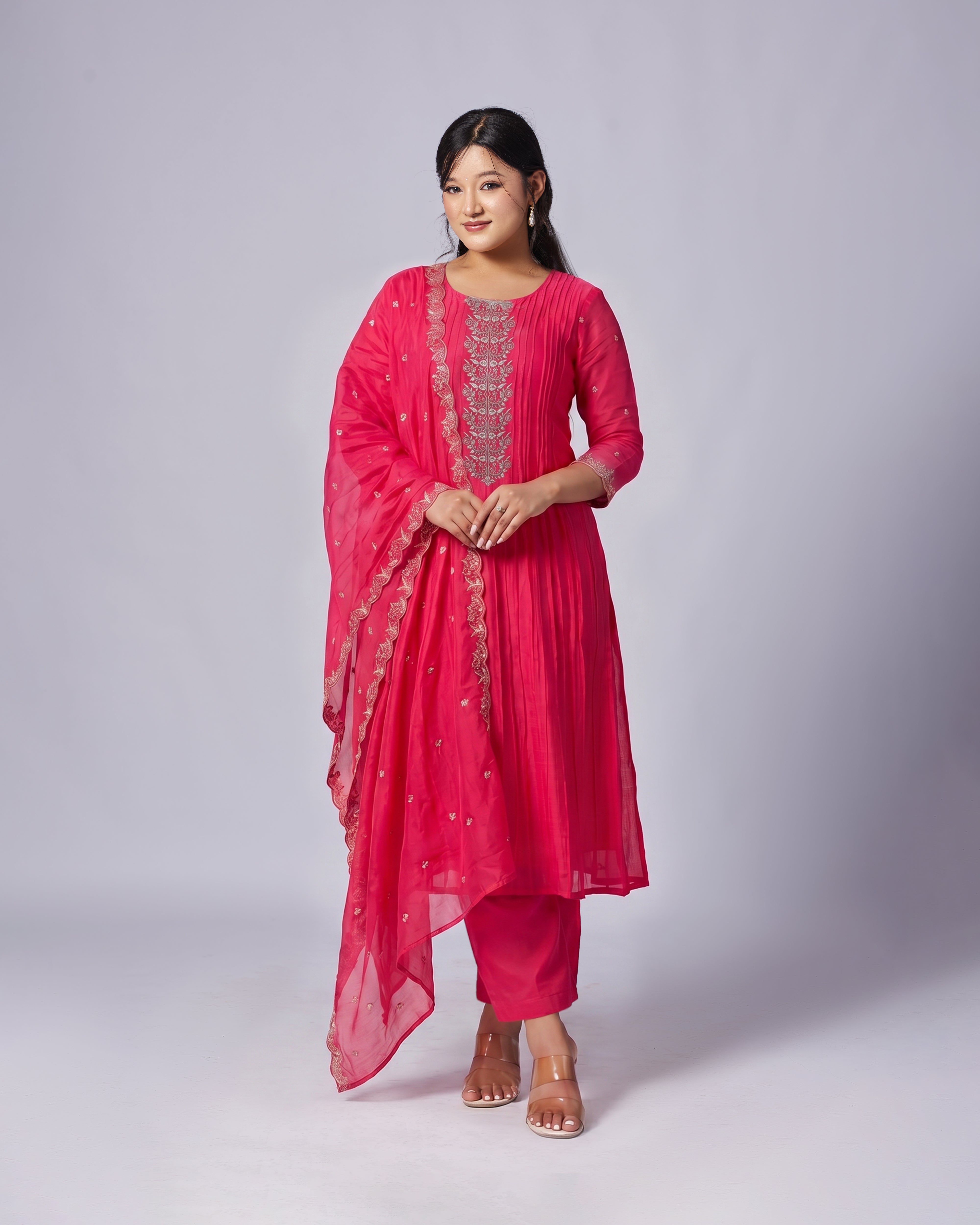 Woman wearing a pink traditional outfit with a matching dupatta on a white background
