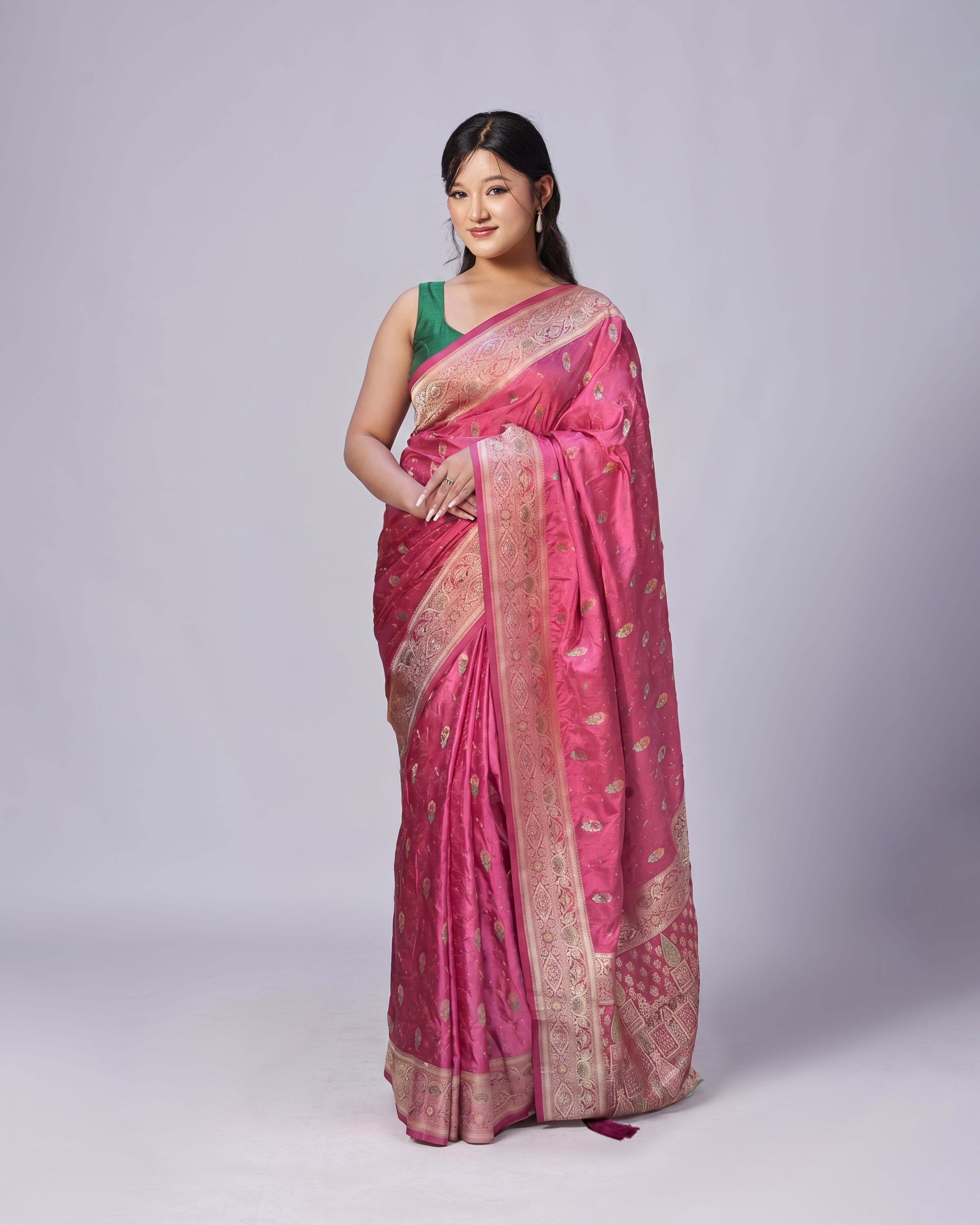Woman wearing a pink saree with a green blouse against a white background