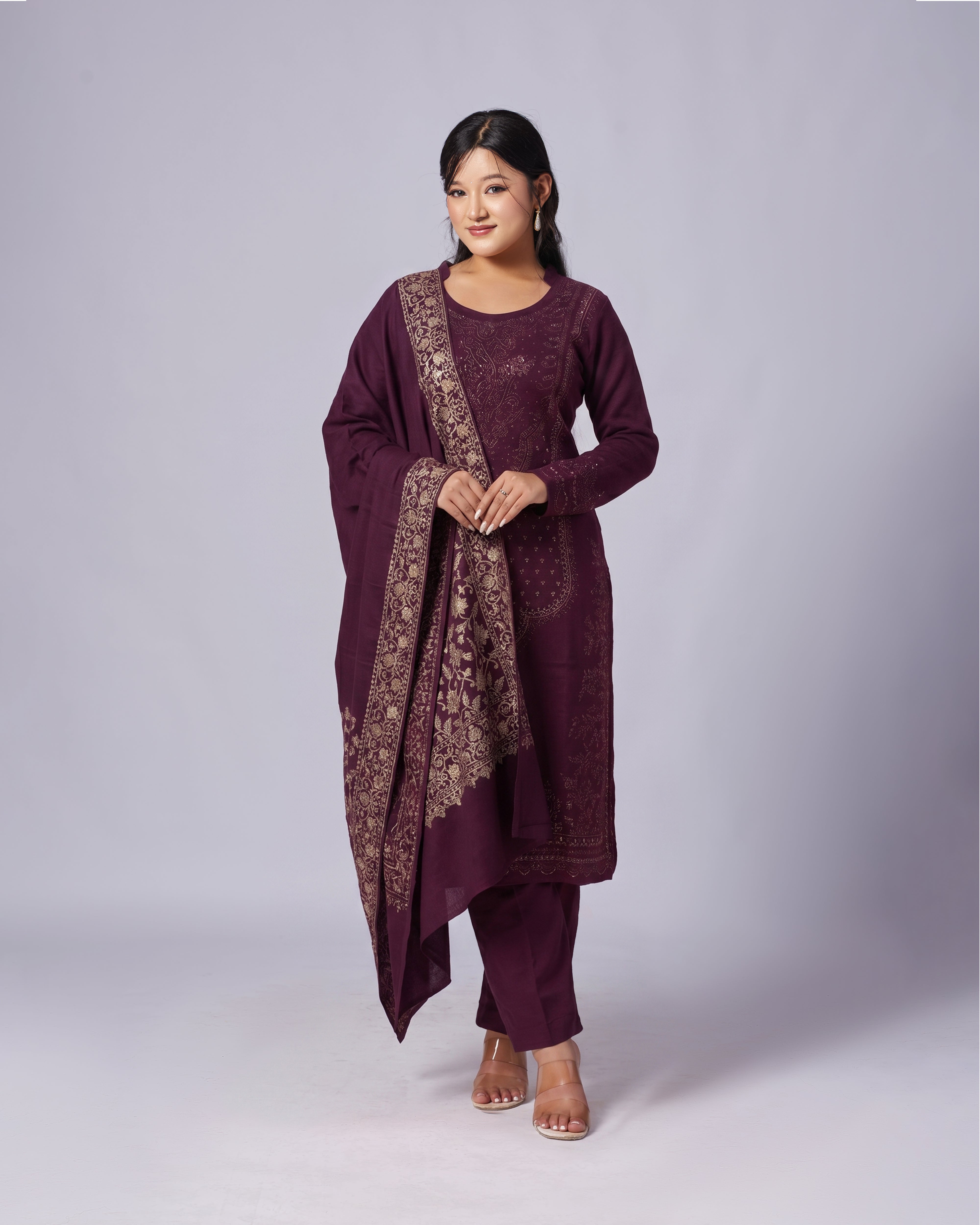 Woman wearing a traditional outfit with a purple kurta and pants on a white background