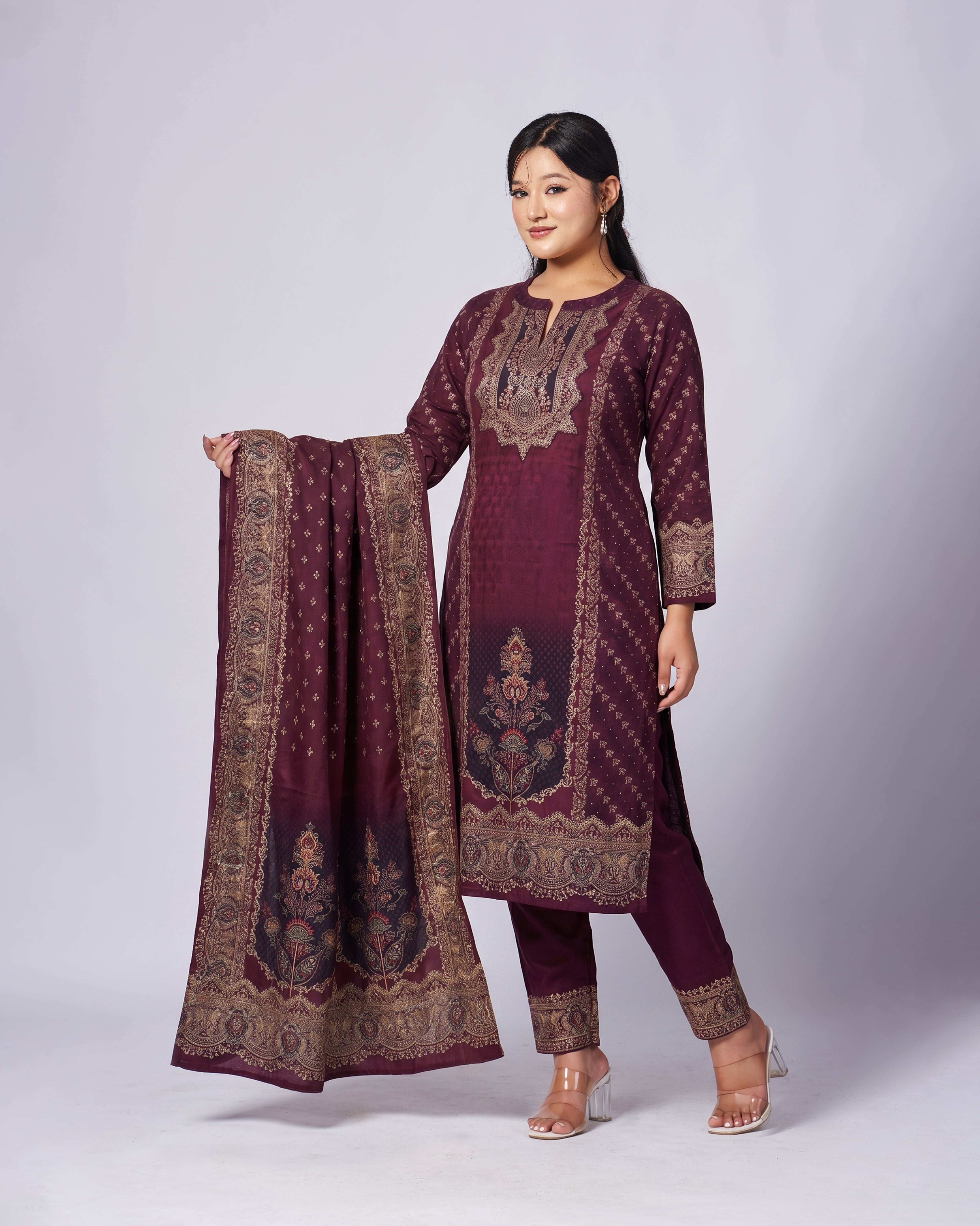 Woman wearing a maroon embroidered traditional outfit with a matching dupatta on a white background