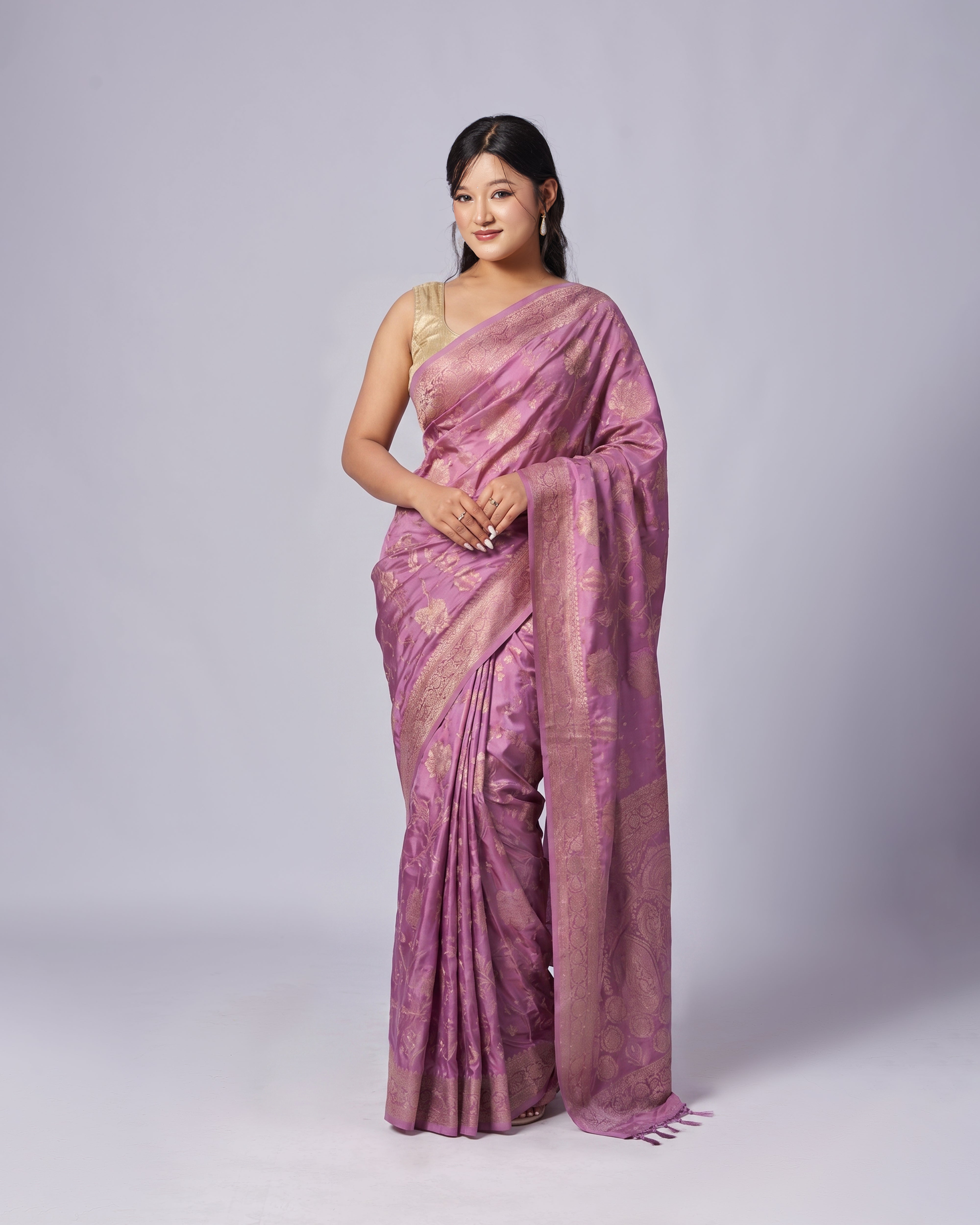 Woman wearing a pink saree with a subtle pattern on a white background