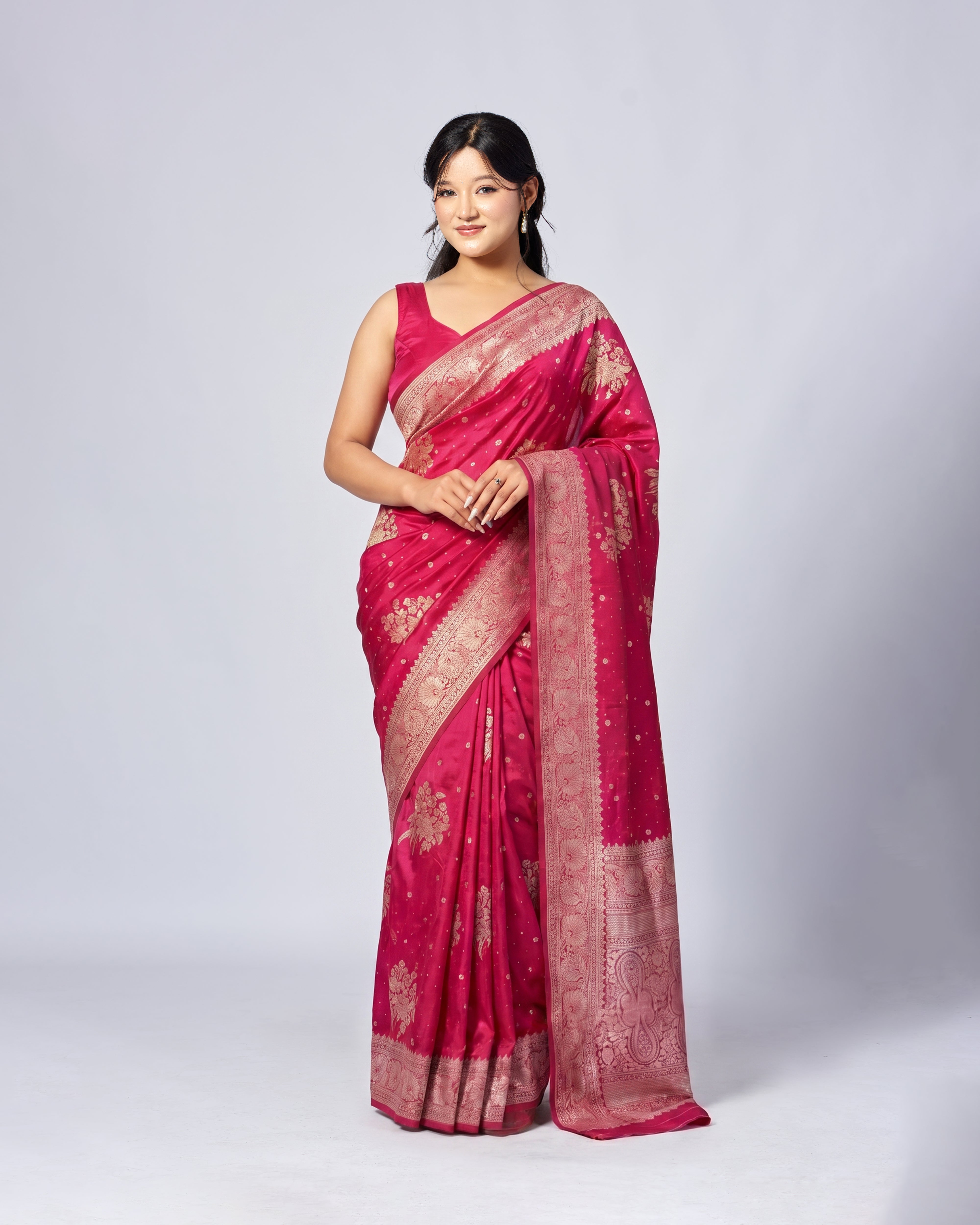 Woman wearing a pink saree with gold patterns on a white background