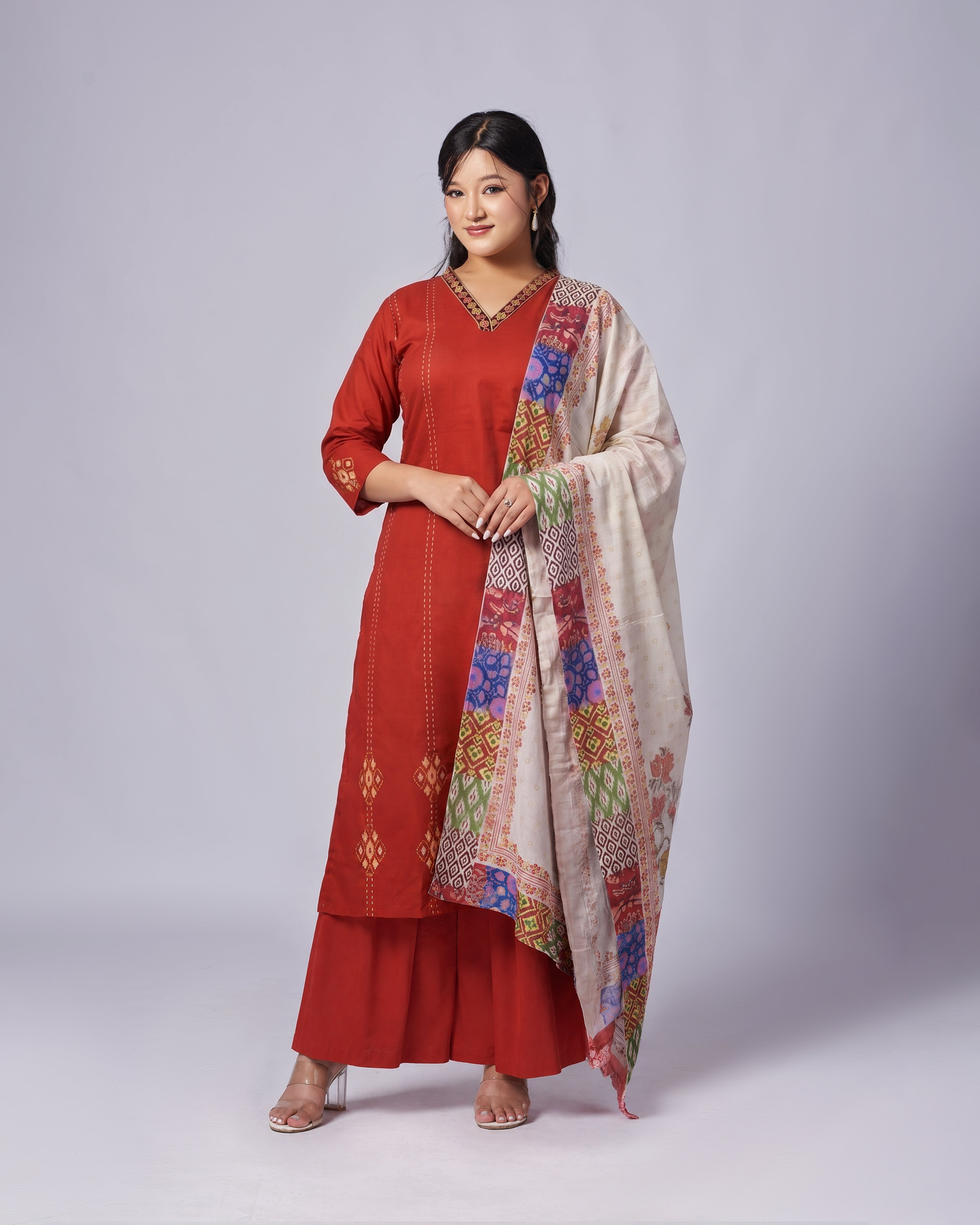 Woman wearing a red traditional outfit with a patterned shawl on a white background