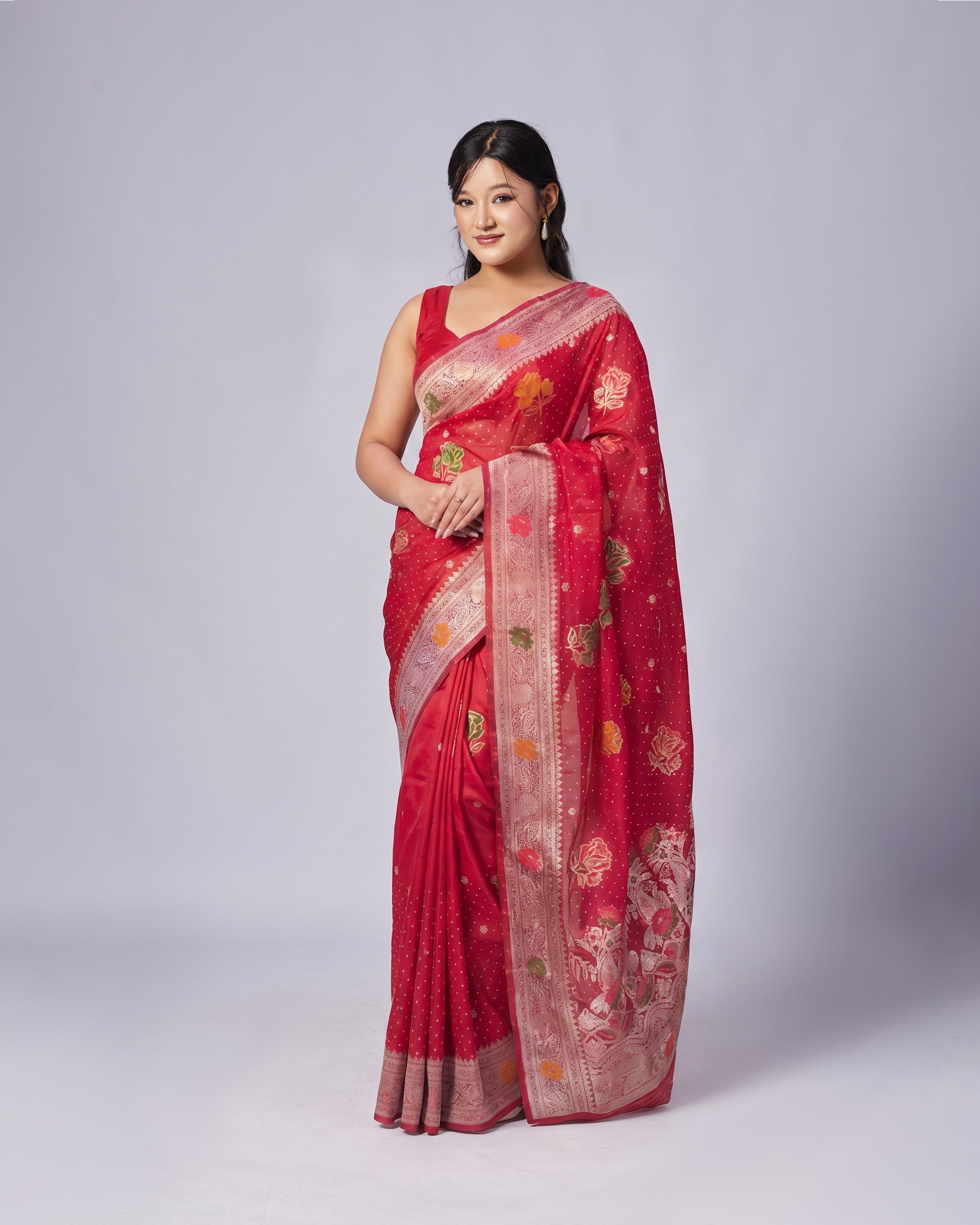 Woman wearing a red saree with gold patterns on a white background