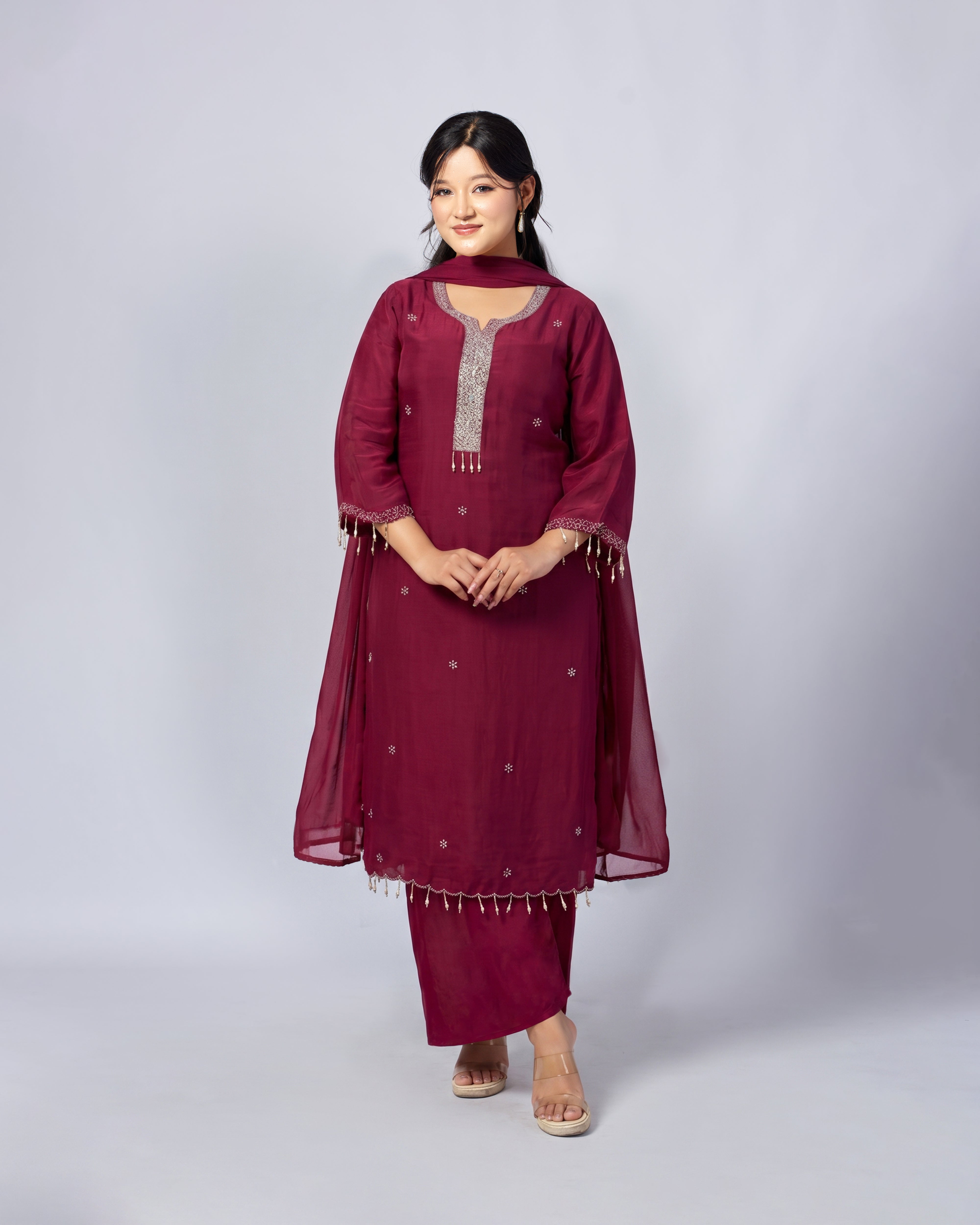 Woman wearing a maroon traditional outfit with a white background