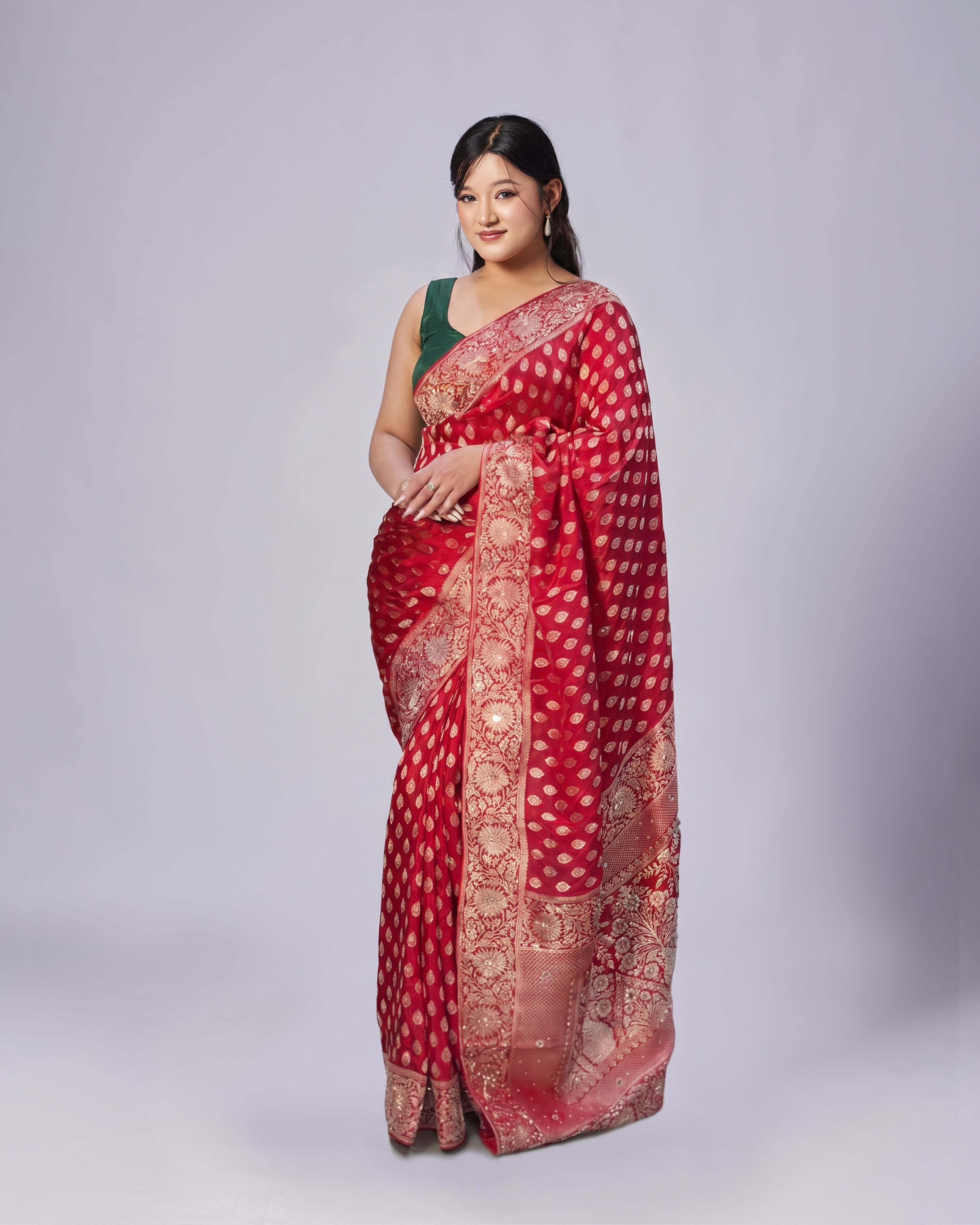 Woman wearing a red saree with gold patterns on a white background