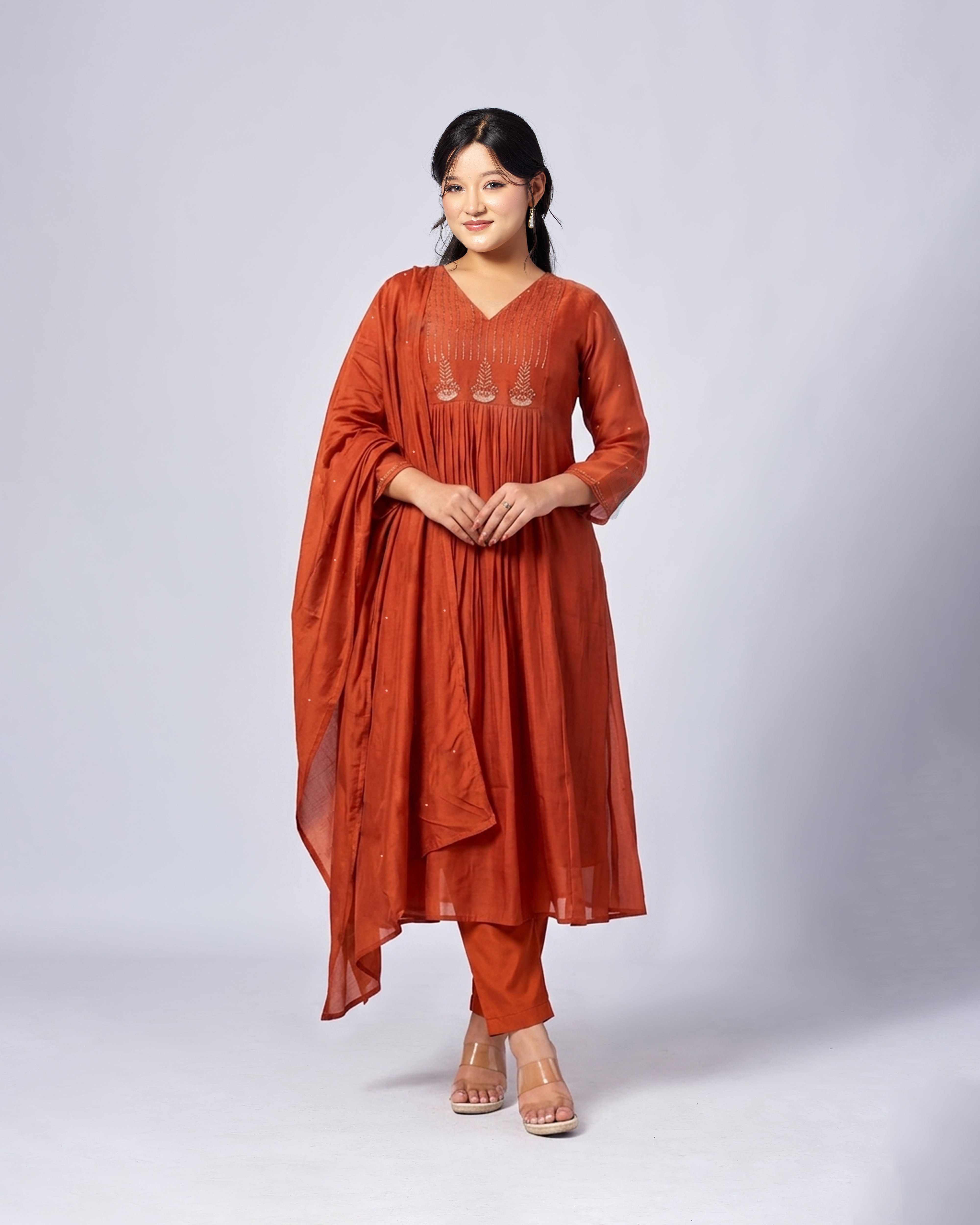 Woman wearing a rust-colored traditional outfit on a white background