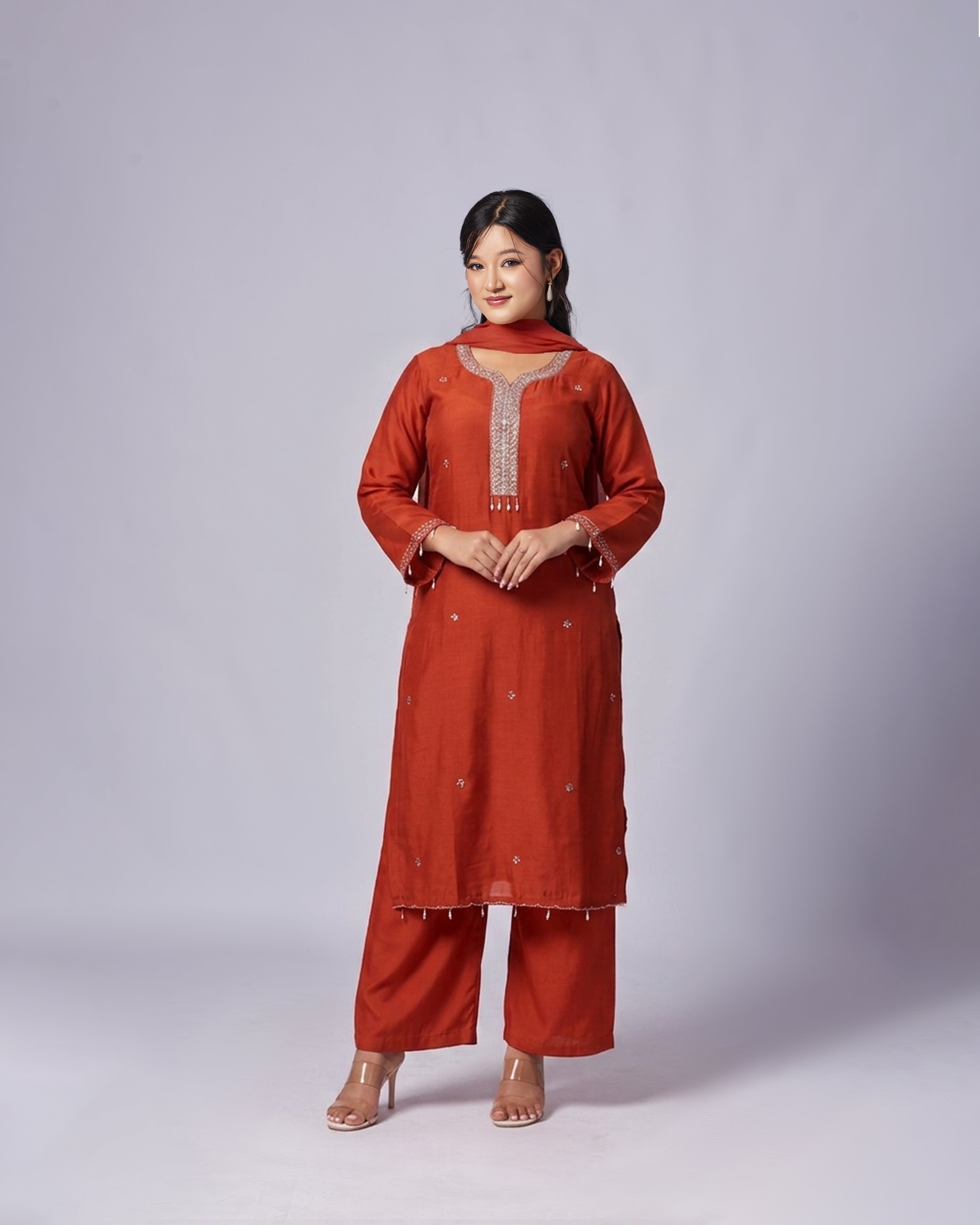 Woman wearing a red traditional outfit with intricate designs on a white background