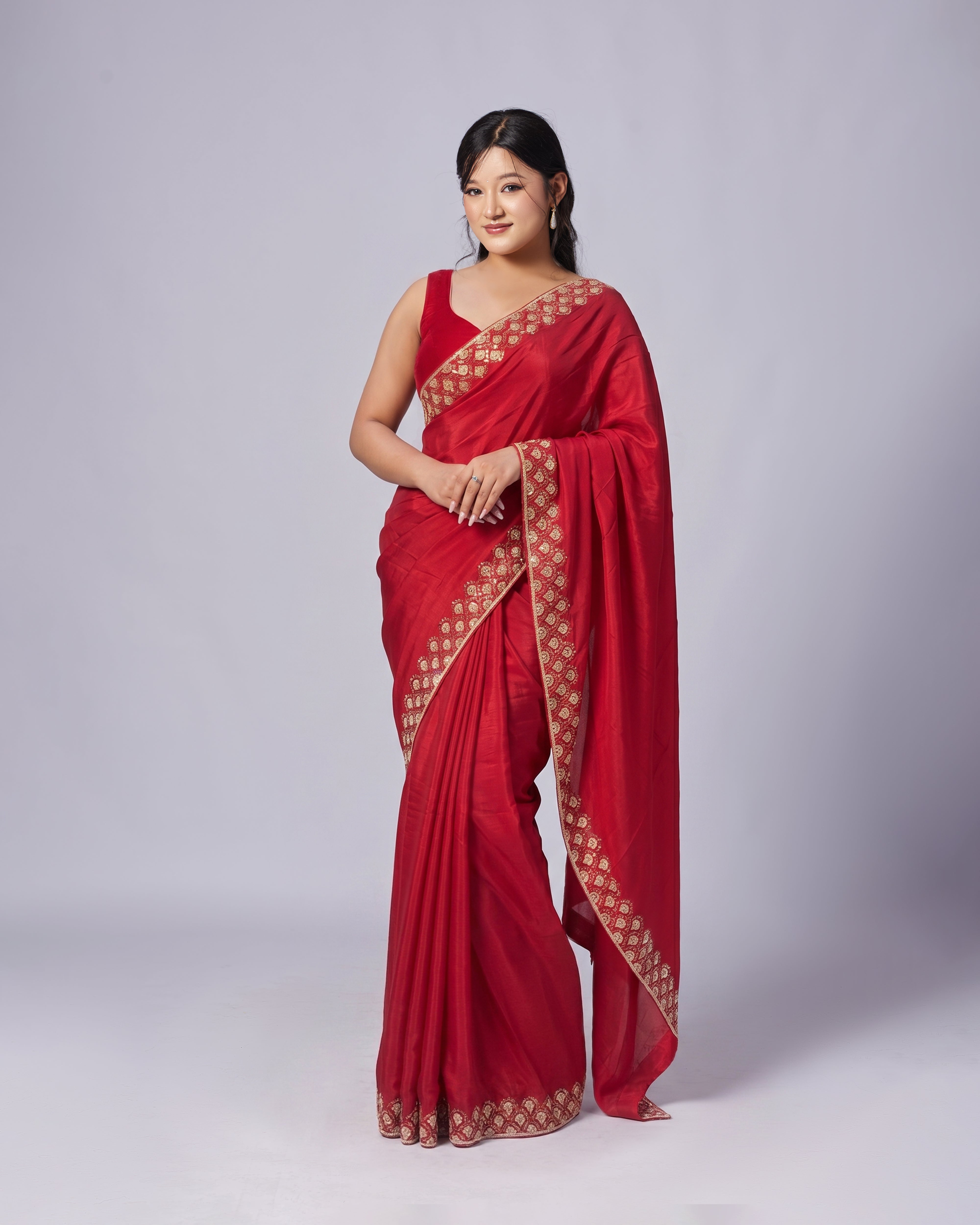 Woman wearing a red saree with gold border on a white background