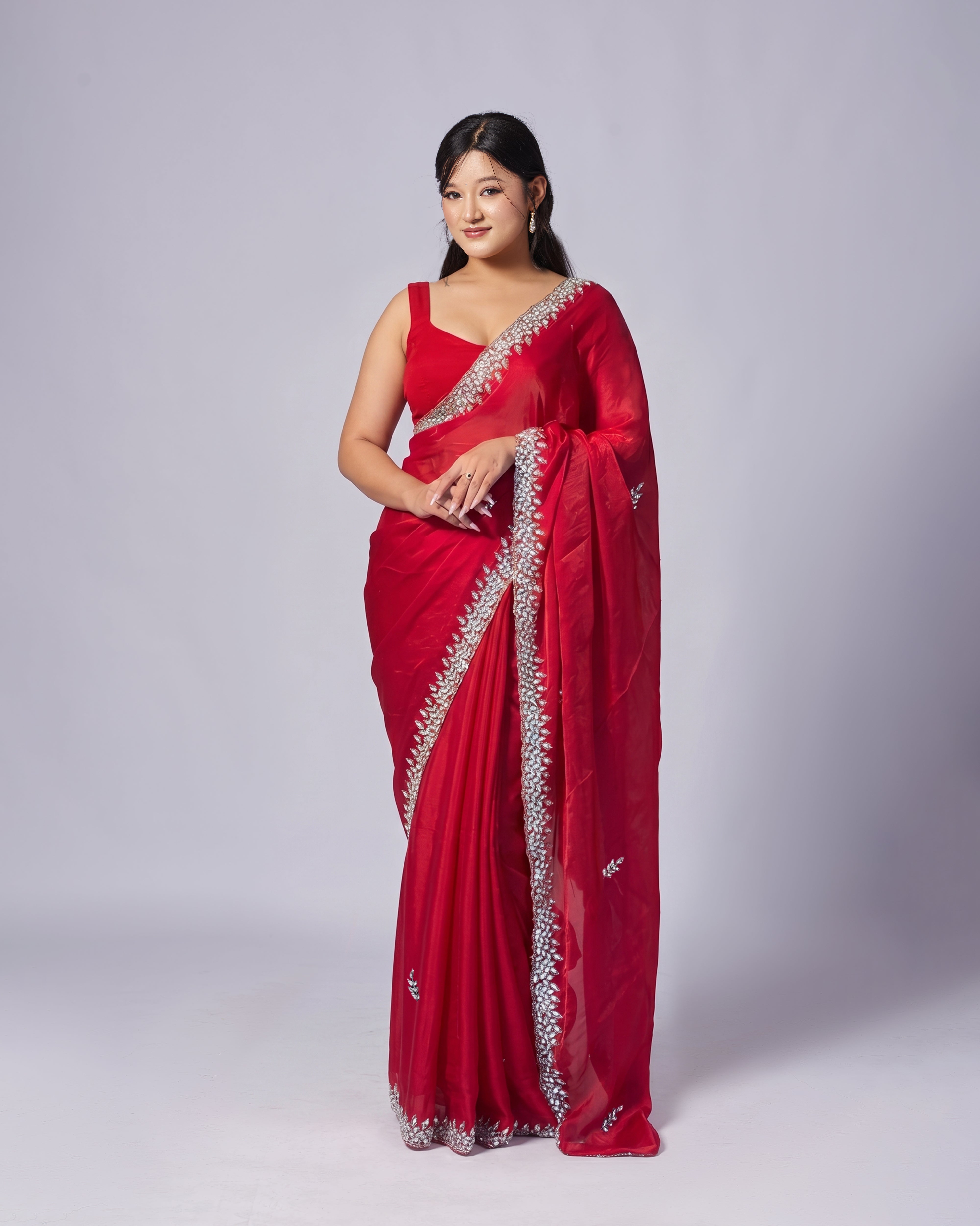 Woman wearing a red saree with silver border on a white background