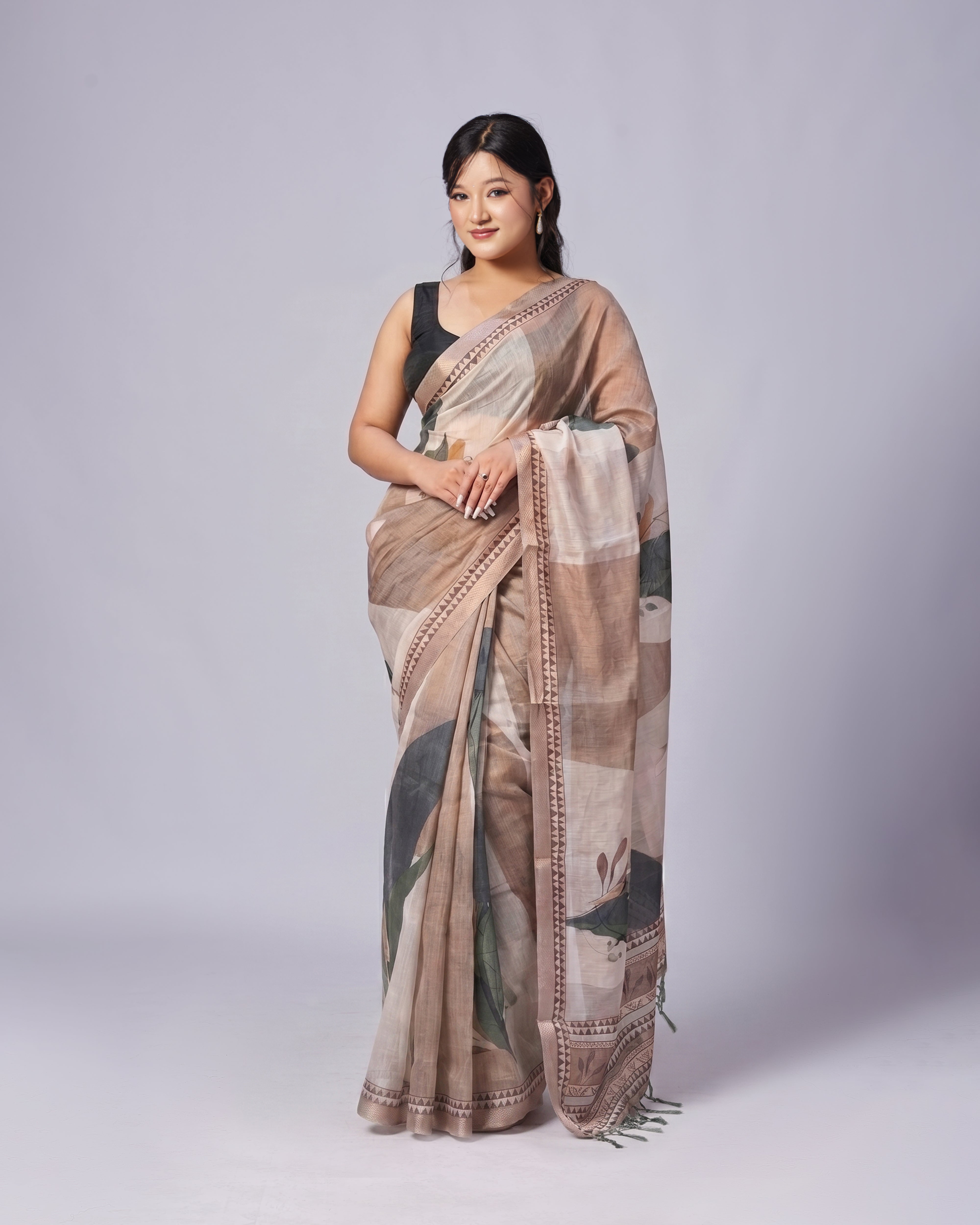 Woman wearing a patterned saree on a plain background