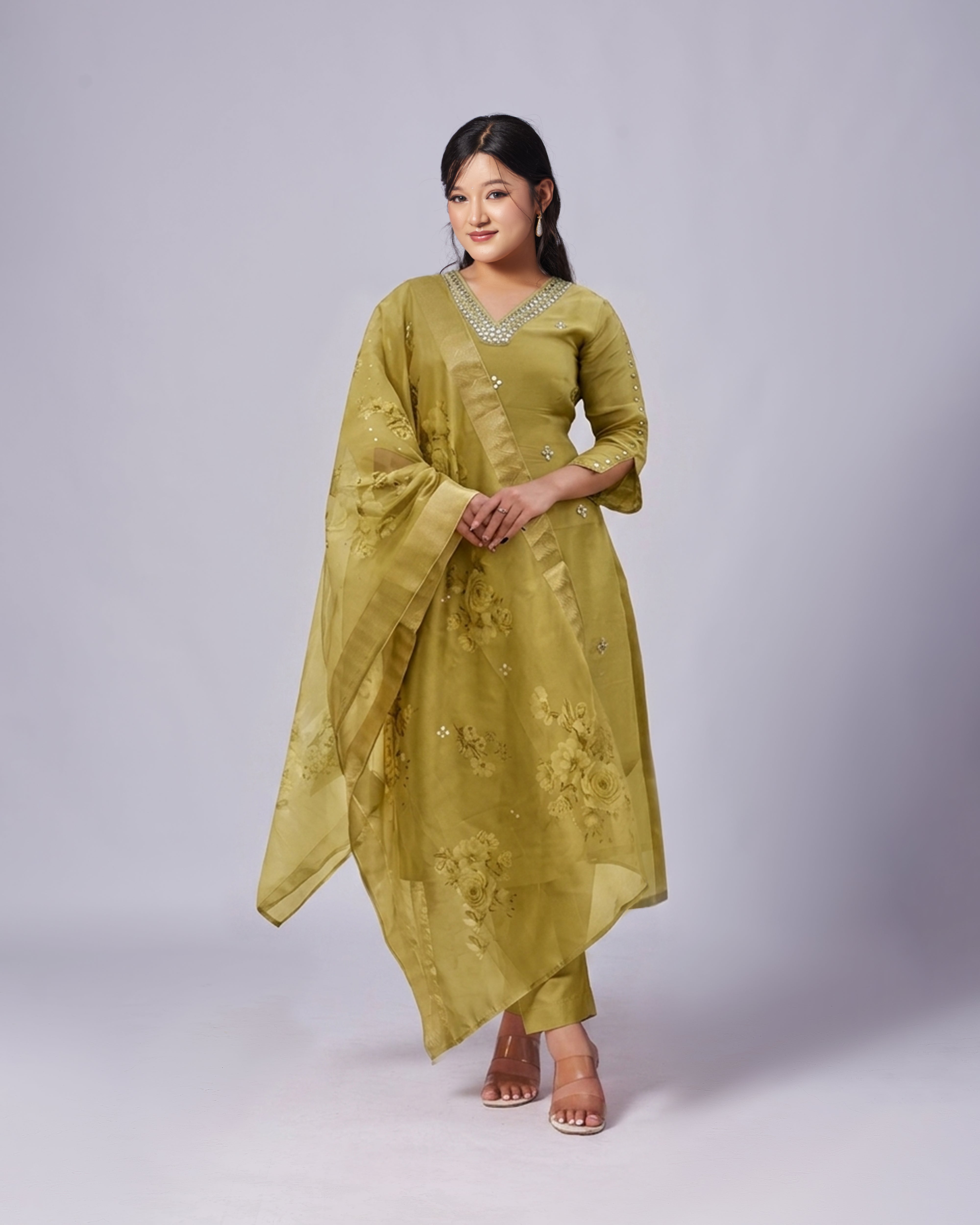 Woman wearing a green traditional outfit with a plain background
