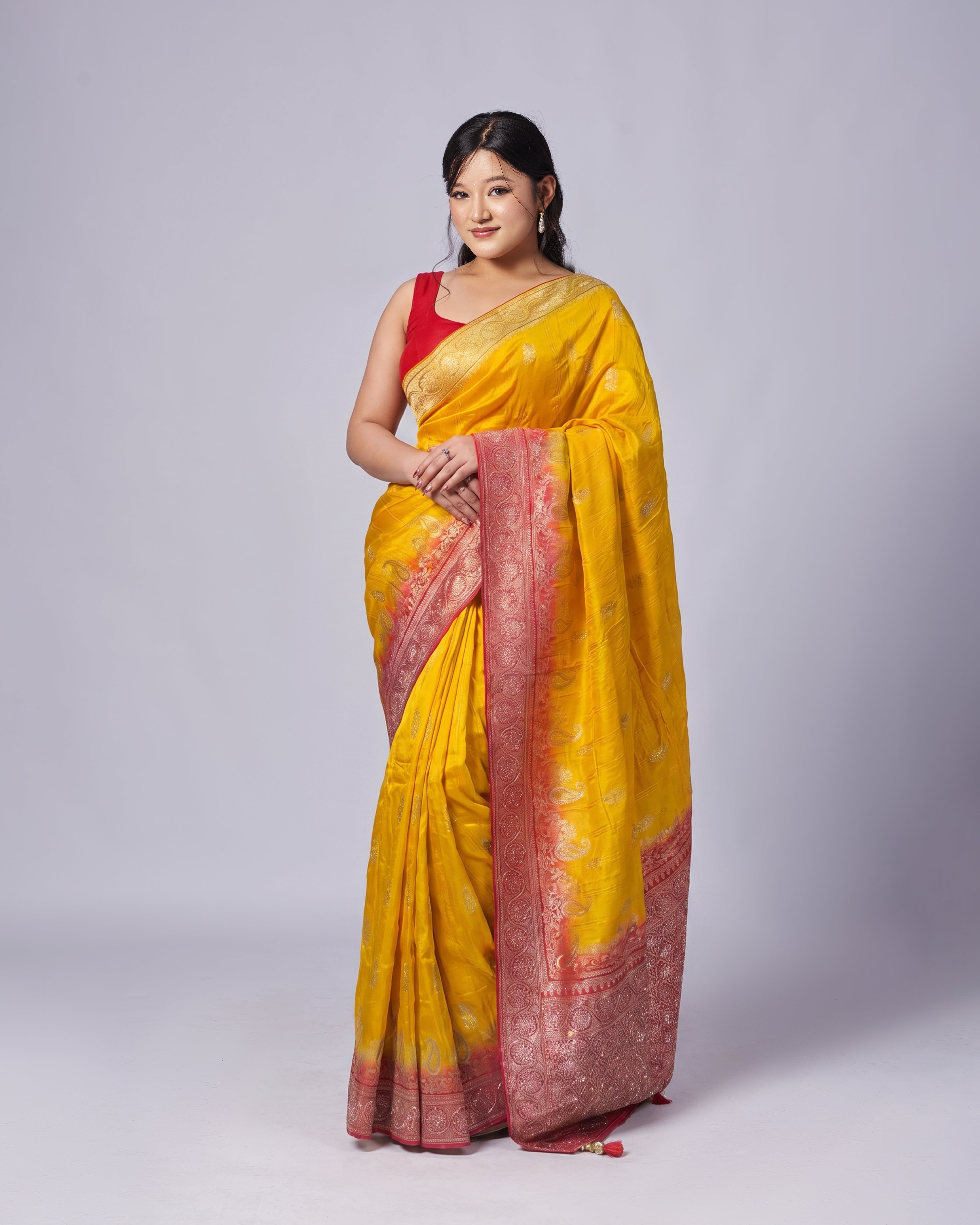 Woman wearing a yellow saree with a red border on a white background